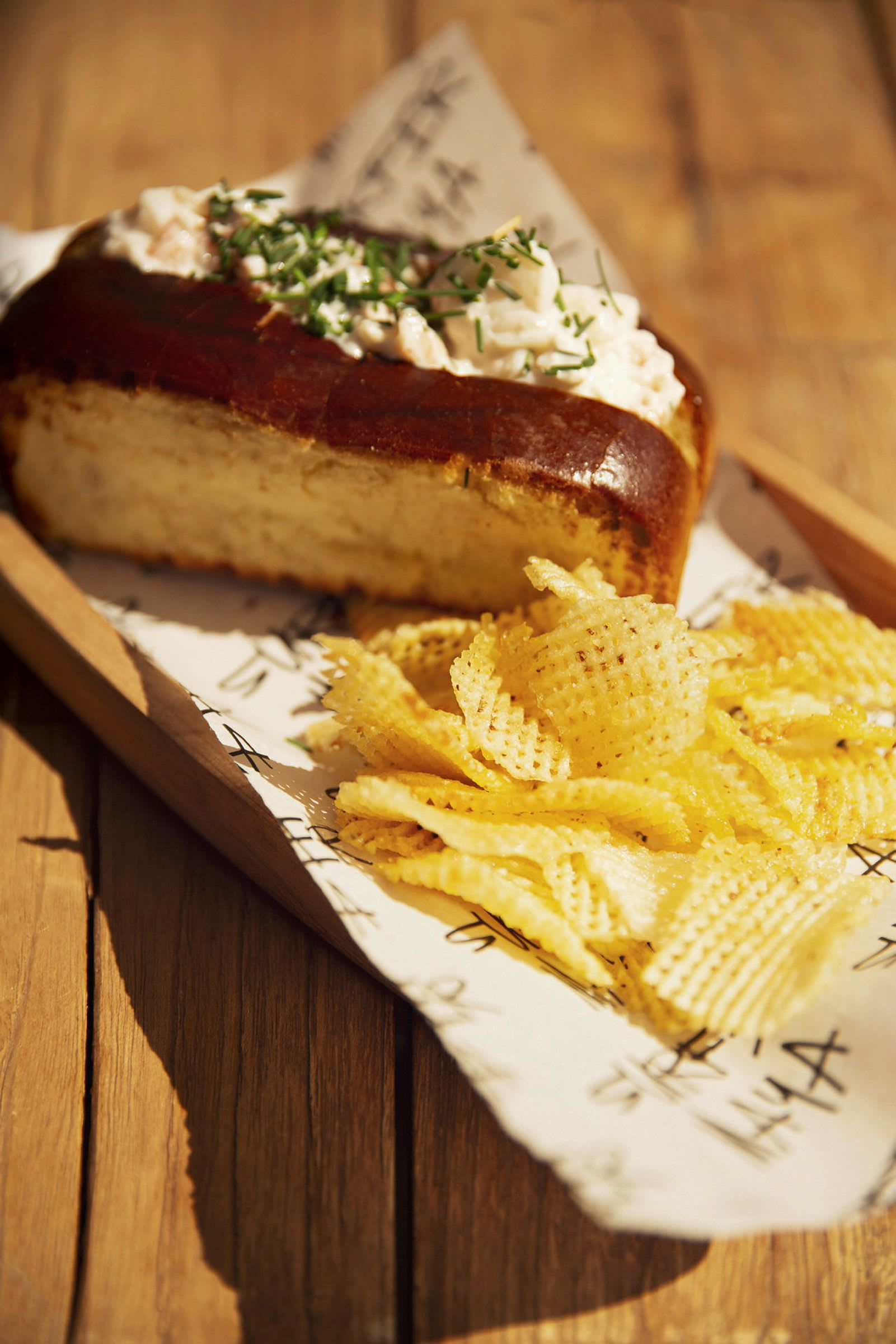 Brød med topping og chips på et træbord. (AI-genereret tekst)