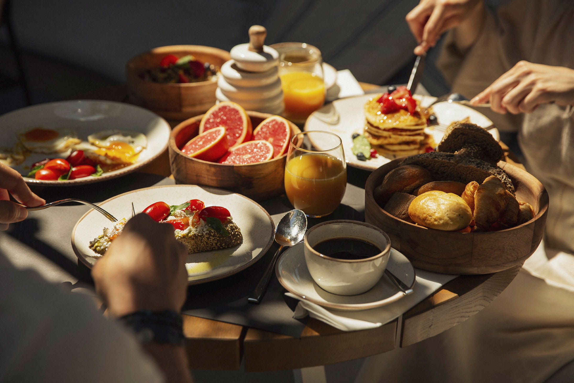 En morgenmad med forskellige madvarer, inklusiv pandekager, grapefrugtskiver, brød og kaffe. (AI-genereret tekst)
