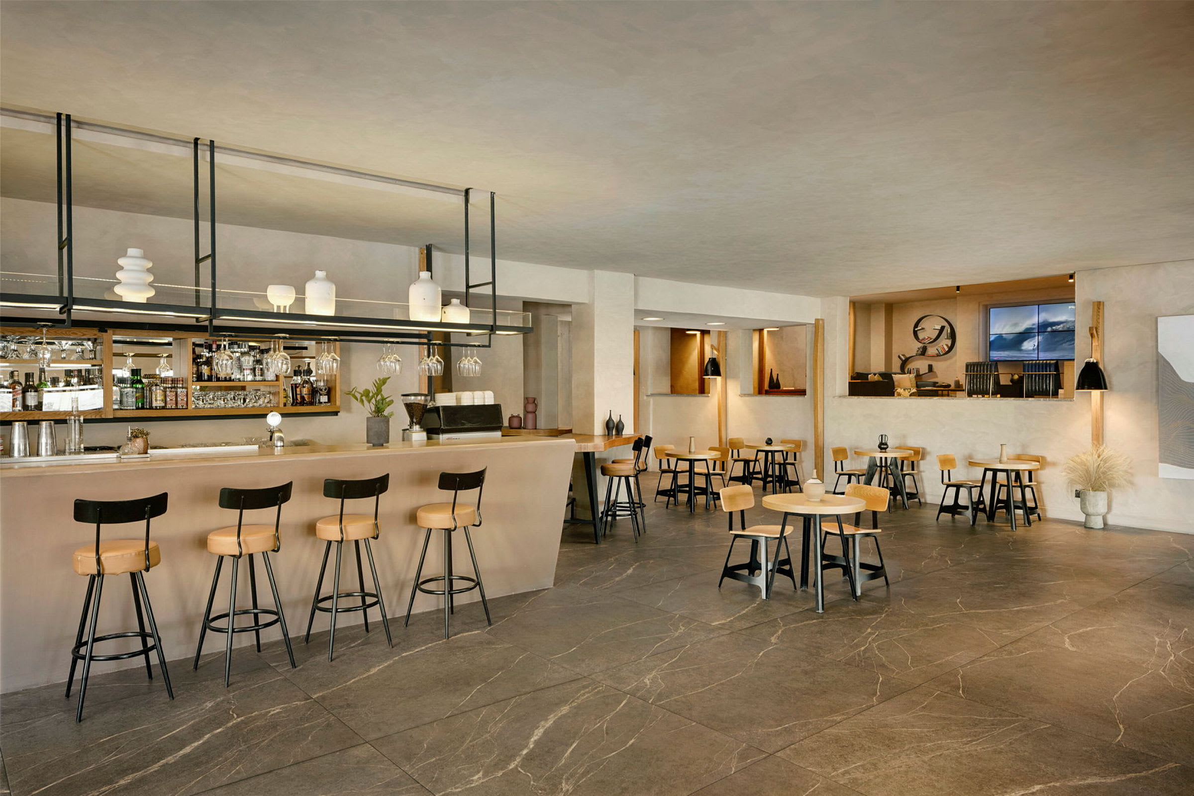 Interiør af en moderne bar og café med borde og stole. (AI-genereret tekst)