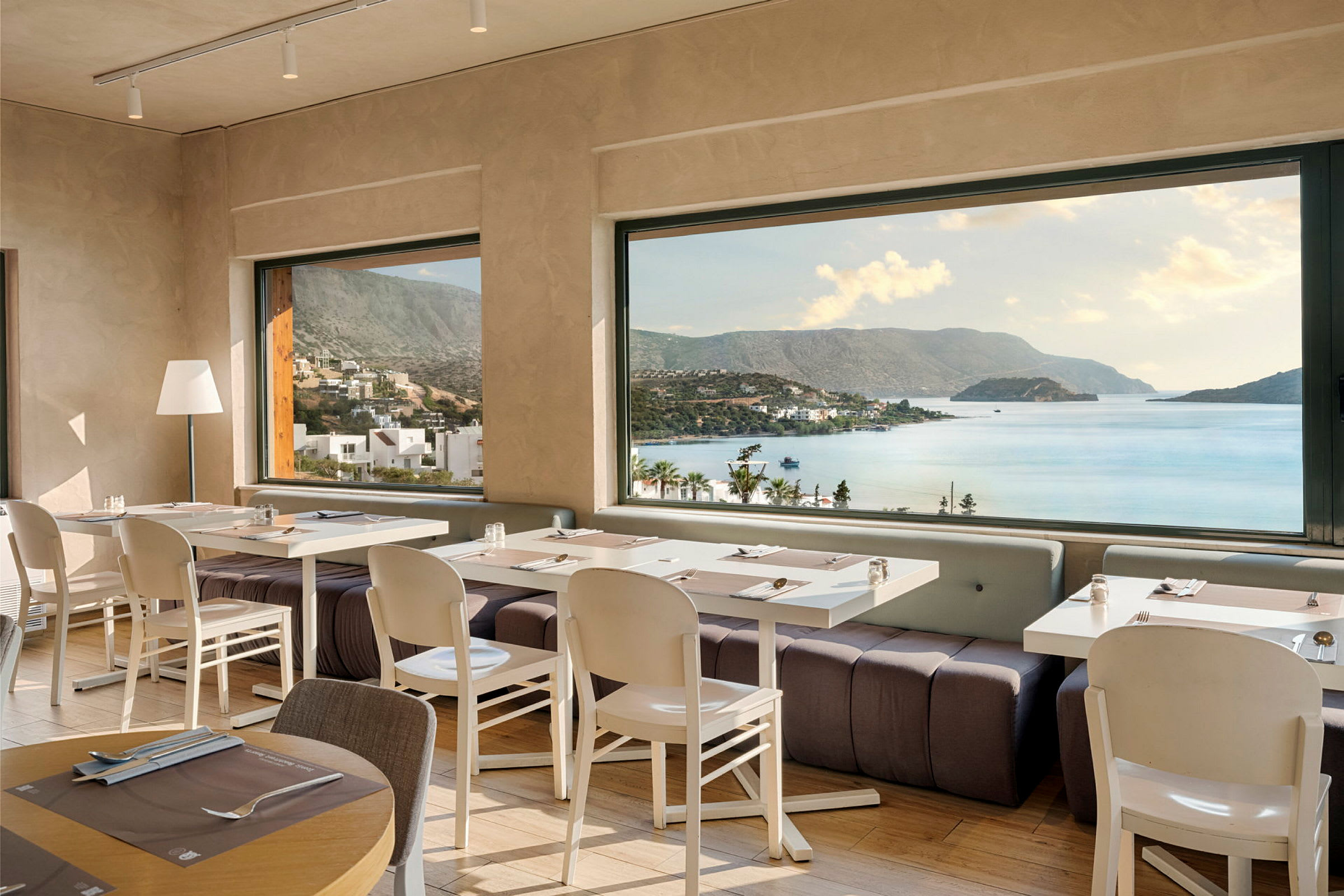 Restaurant med dækkede borde og panoramaudsigt over kyst og bjerge. (AI-genereret tekst)