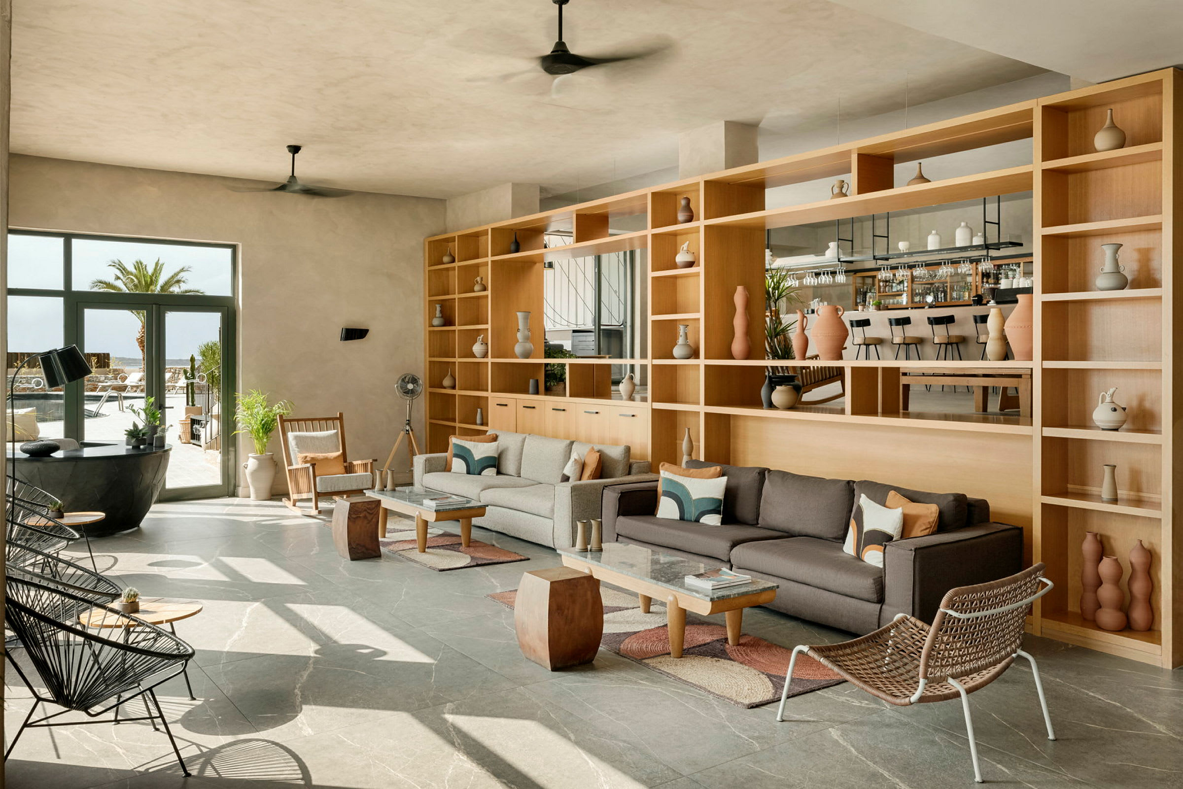 Et moderne loungeområde med sofaer og hylder, store vinduer og en bar i baggrunden. (AI-genereret tekst)