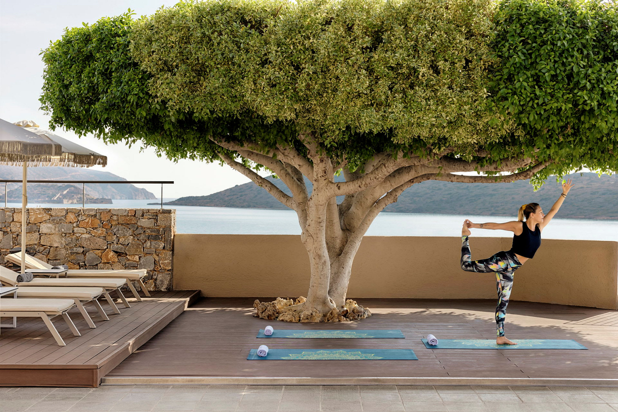 En person laver yoga på en terrasse med udsigt over havet. (AI-genereret tekst)
