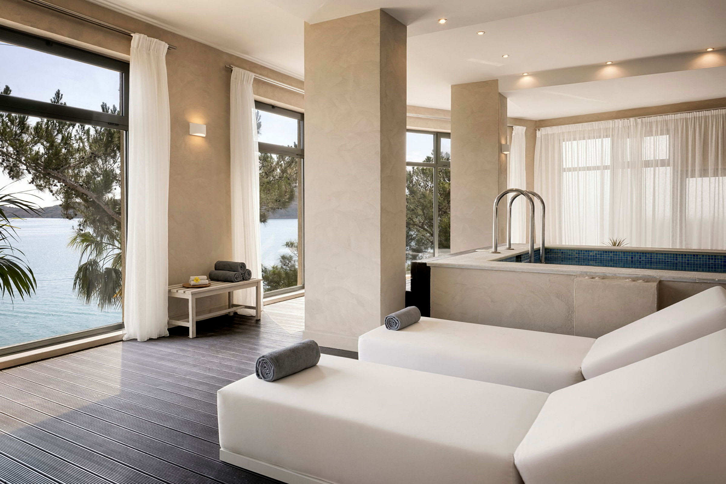 Et moderne spa med liggestole og en indendørs pool med udsigt over havet. (AI-genereret tekst)