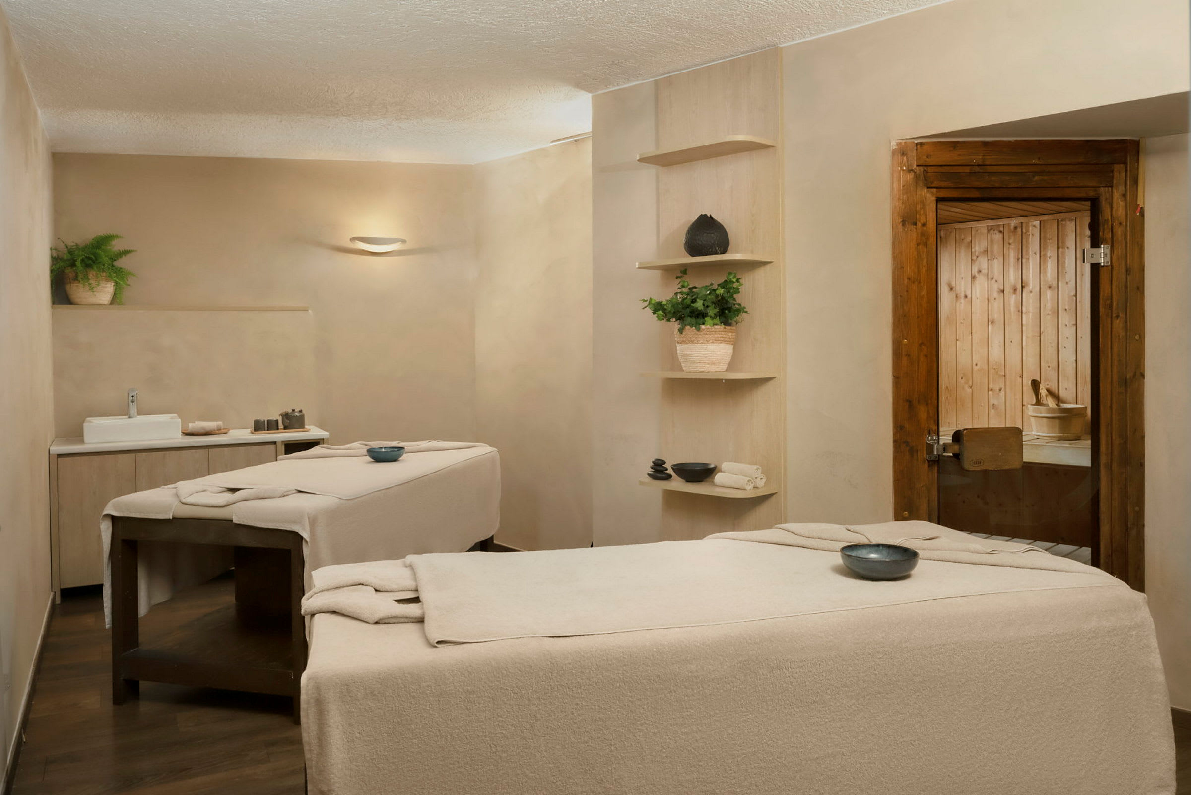 To massageborde i et spa-rum med neutrale farver, dekorative genstande og planter. (AI-genereret tekst)