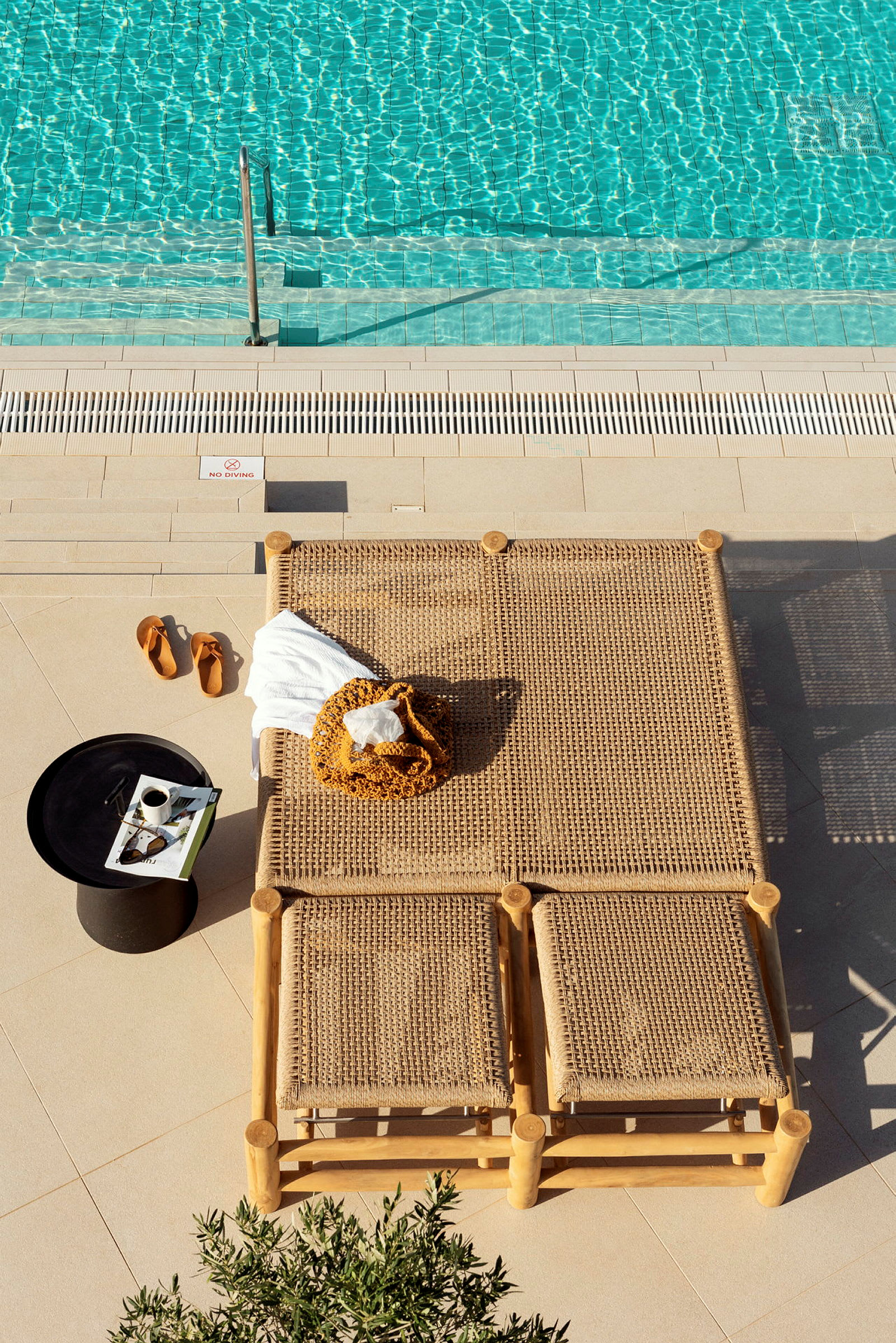 En pool med klart vand, liggestole og et bord med en kaffekop ved kanten. (AI-genereret tekst)