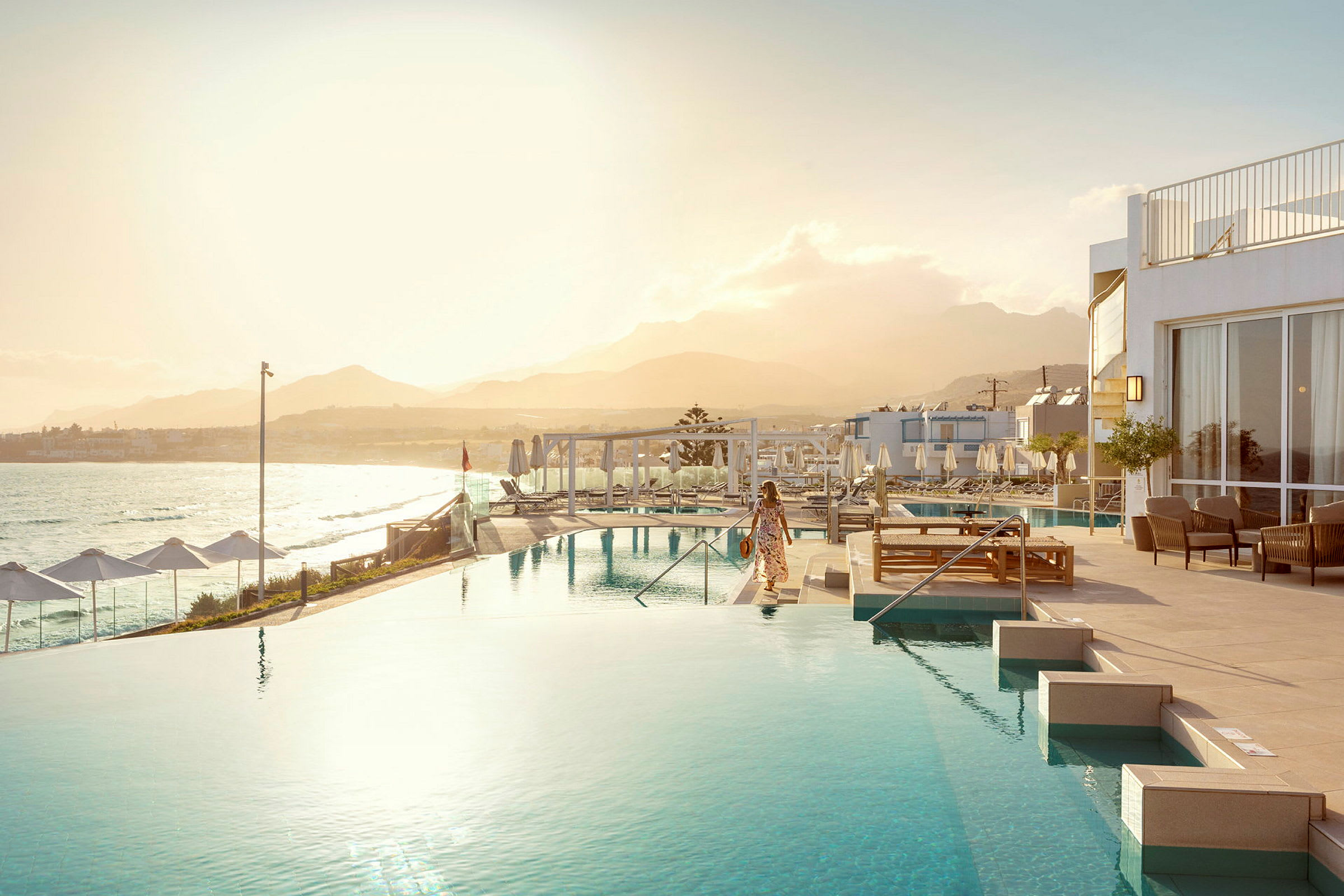 En kvinde ved en infinitypool med havet og en bjergkæde i baggrunden. (AI-genereret tekst)