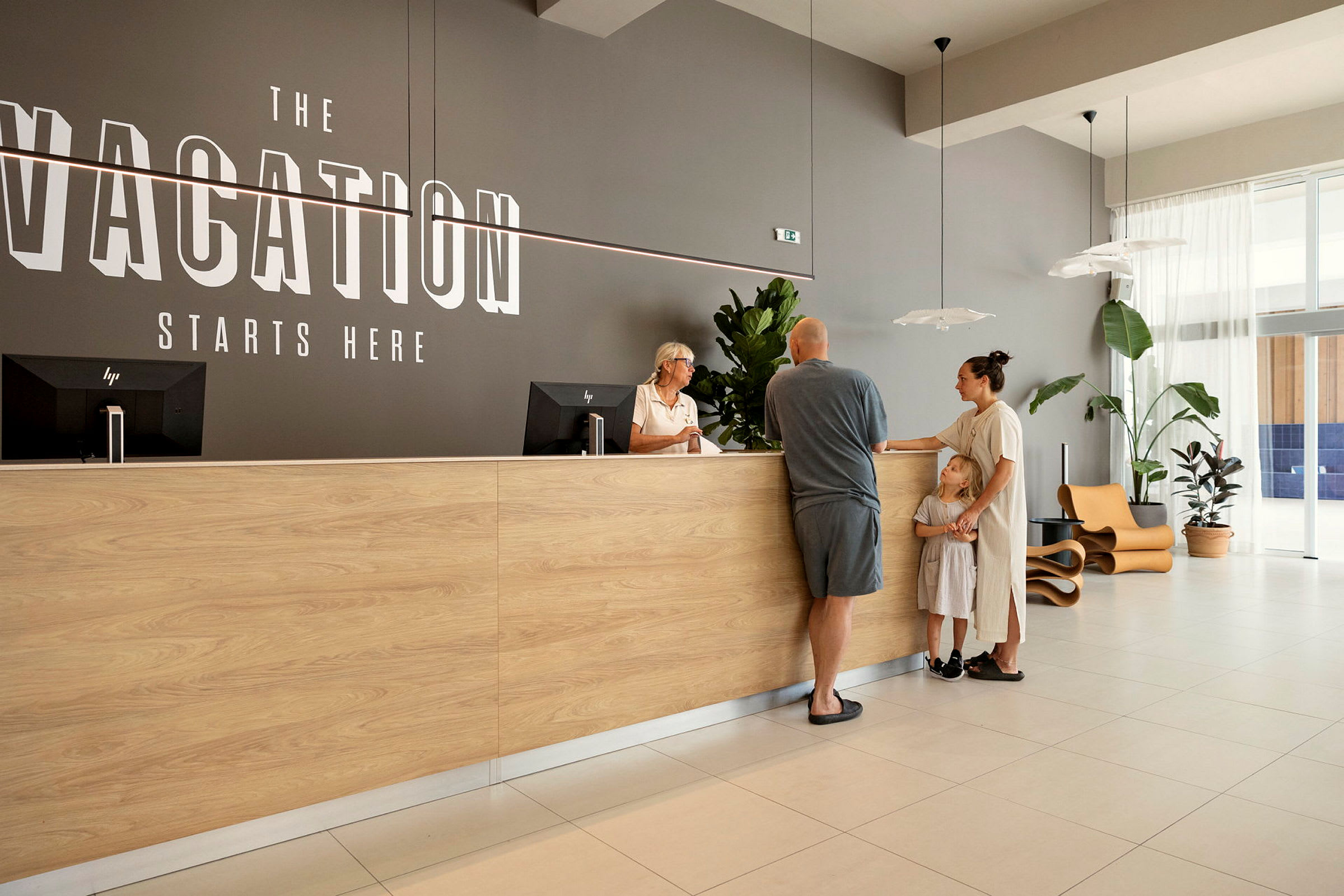 En reception med en trædisk og teksten "Vacation Starts Here" på væggen. (AI-genereret tekst)
