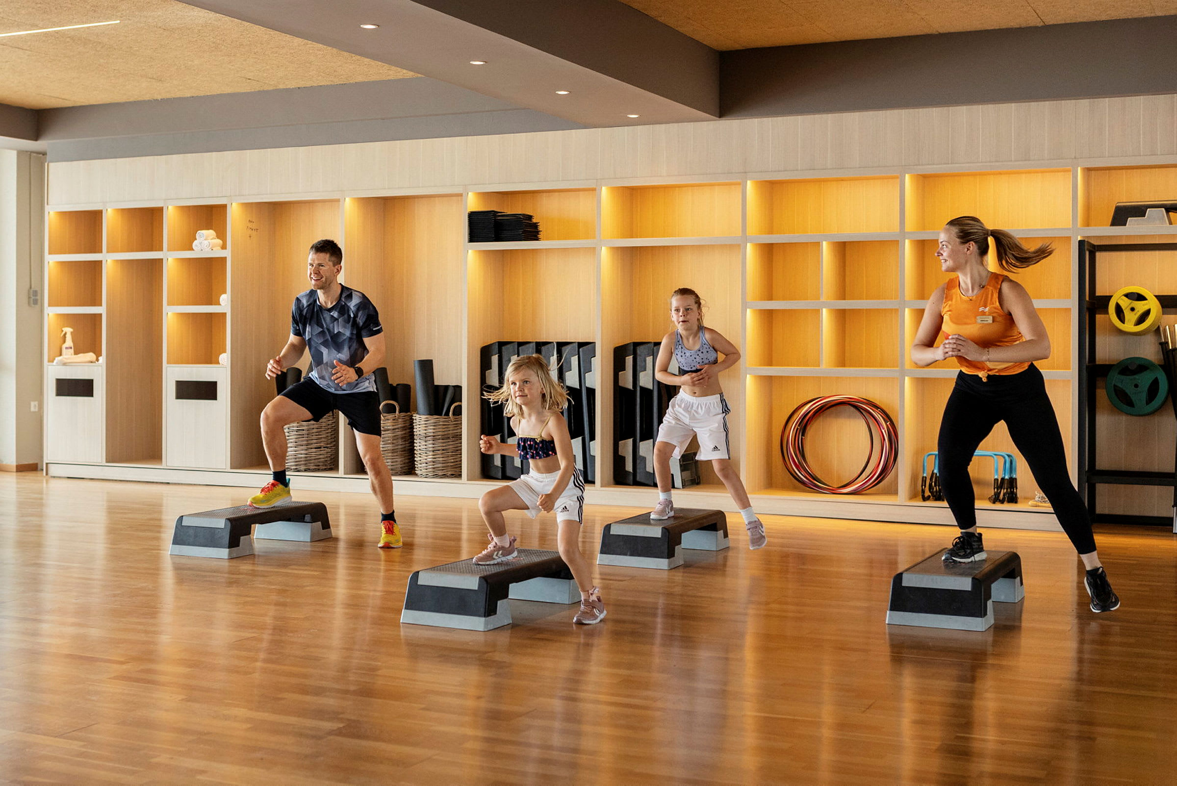 Fire personer træner med stepbrædder i et fitnesscenter. (AI-genereret tekst)