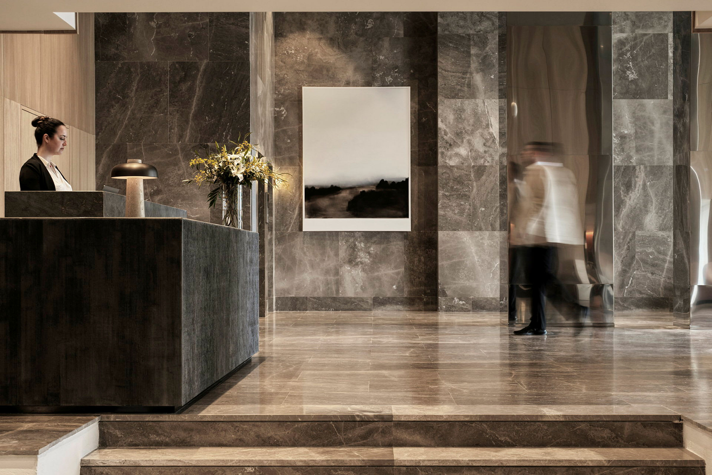 Hotellets lobby med moderne marmorinretning og et receptionsområde. (AI-genereret tekst)