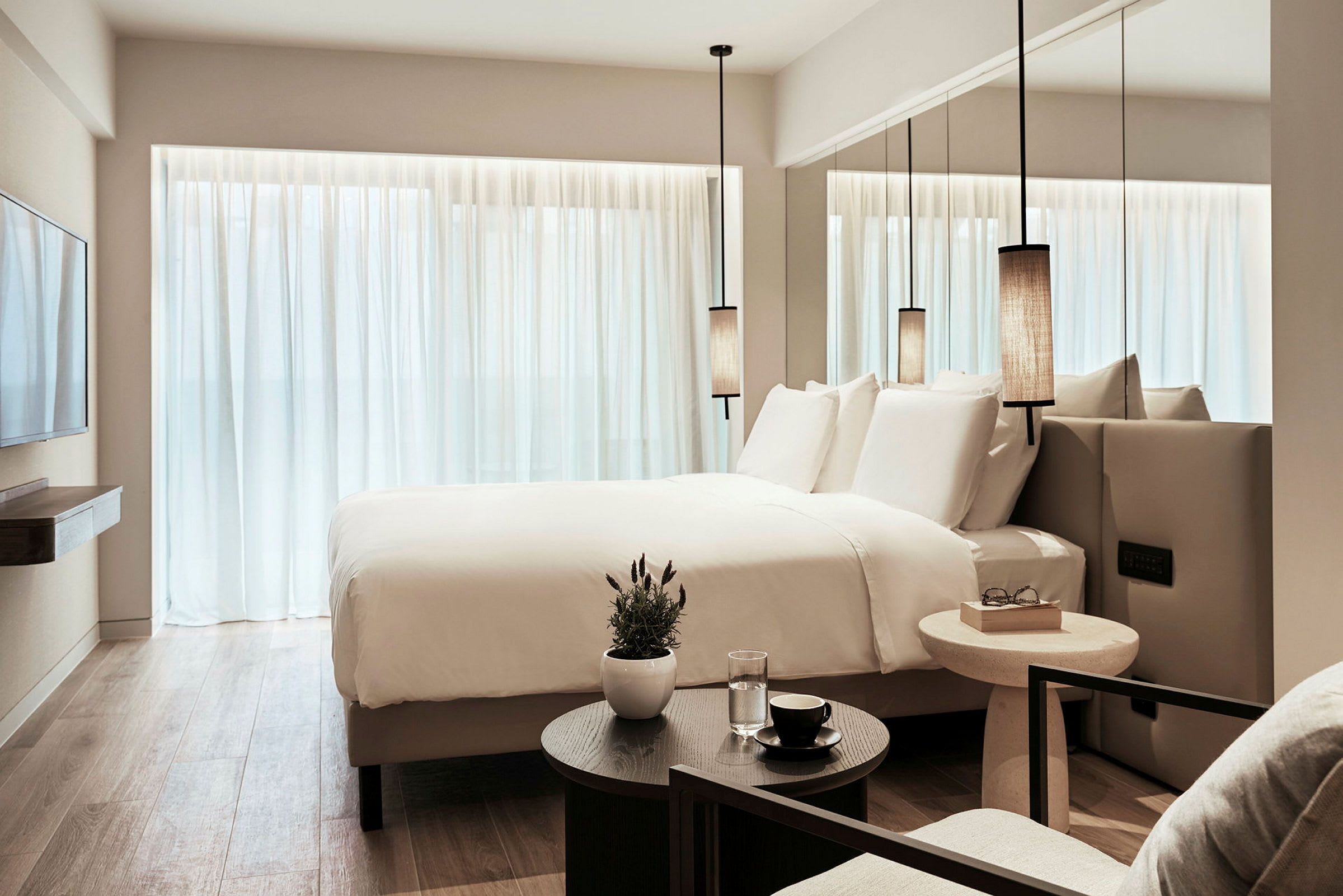 Et moderne hotelværelse med en stor seng, hvide lagner og minimalistisk indretning. (AI-genereret tekst)