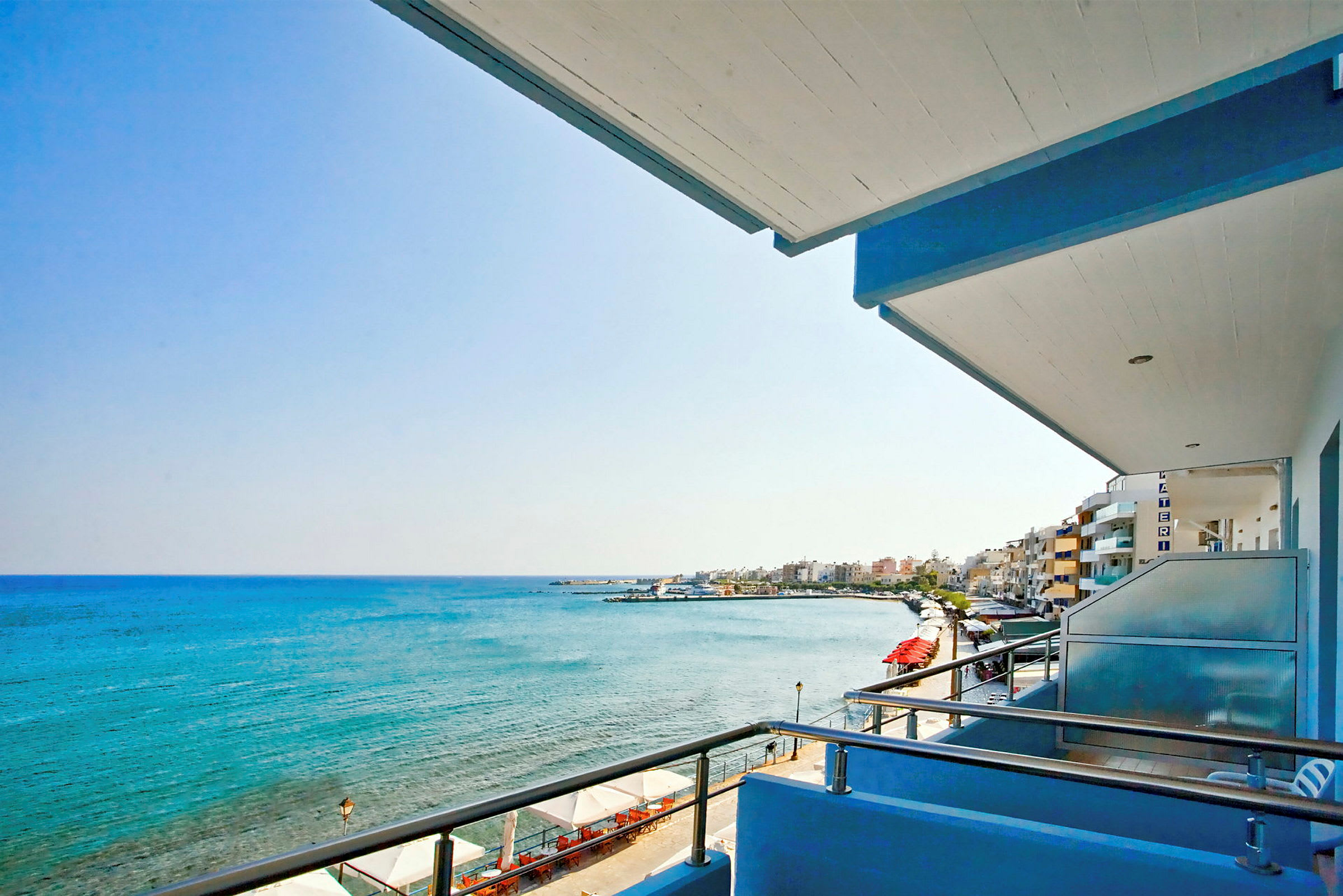 Udsigt fra en balkon over havet og en strandpromenade. (AI-genereret tekst)