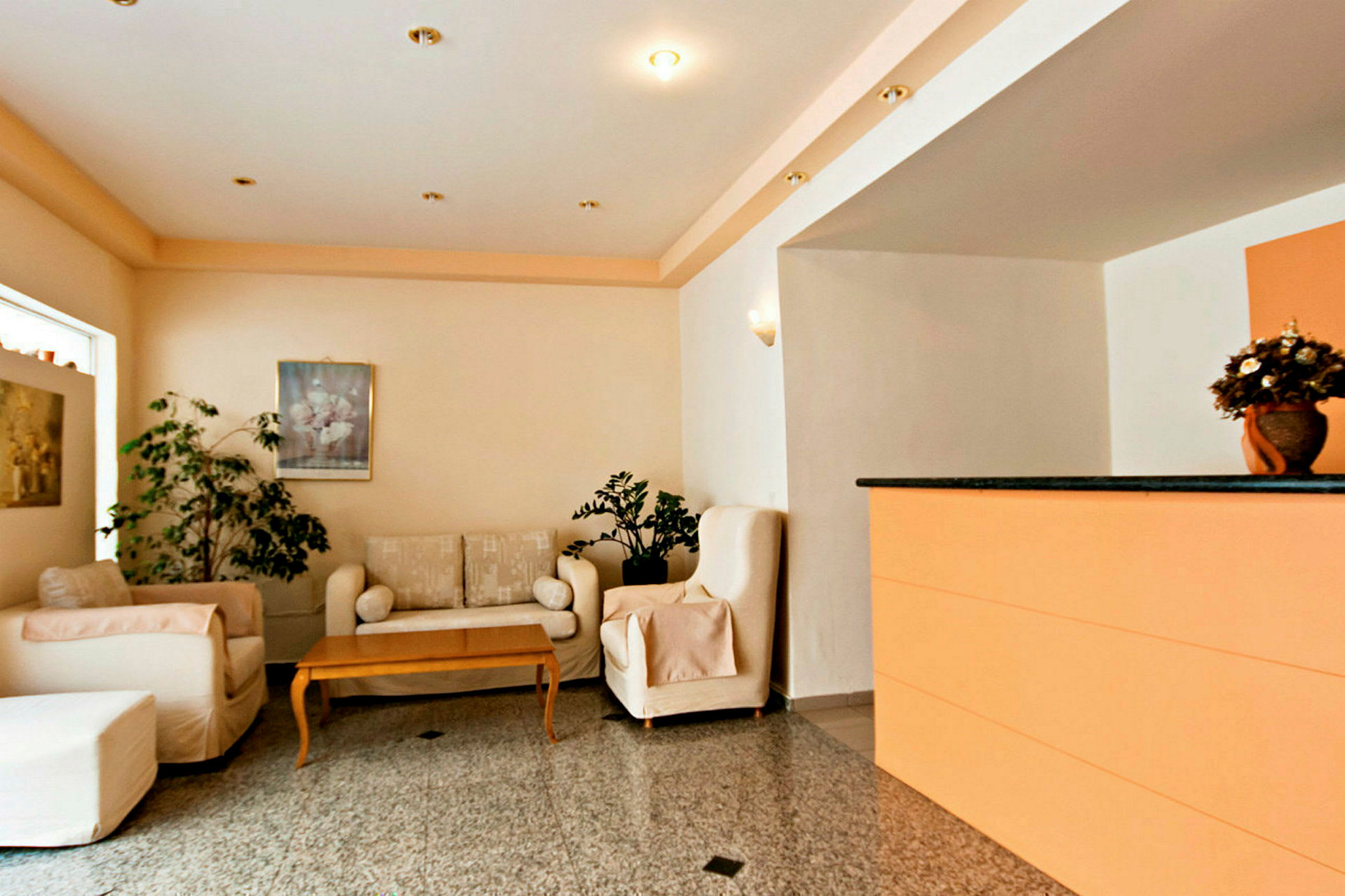 Lobbyområde med sofaer, bord, dekorative planter og en reception. (AI-genereret tekst)