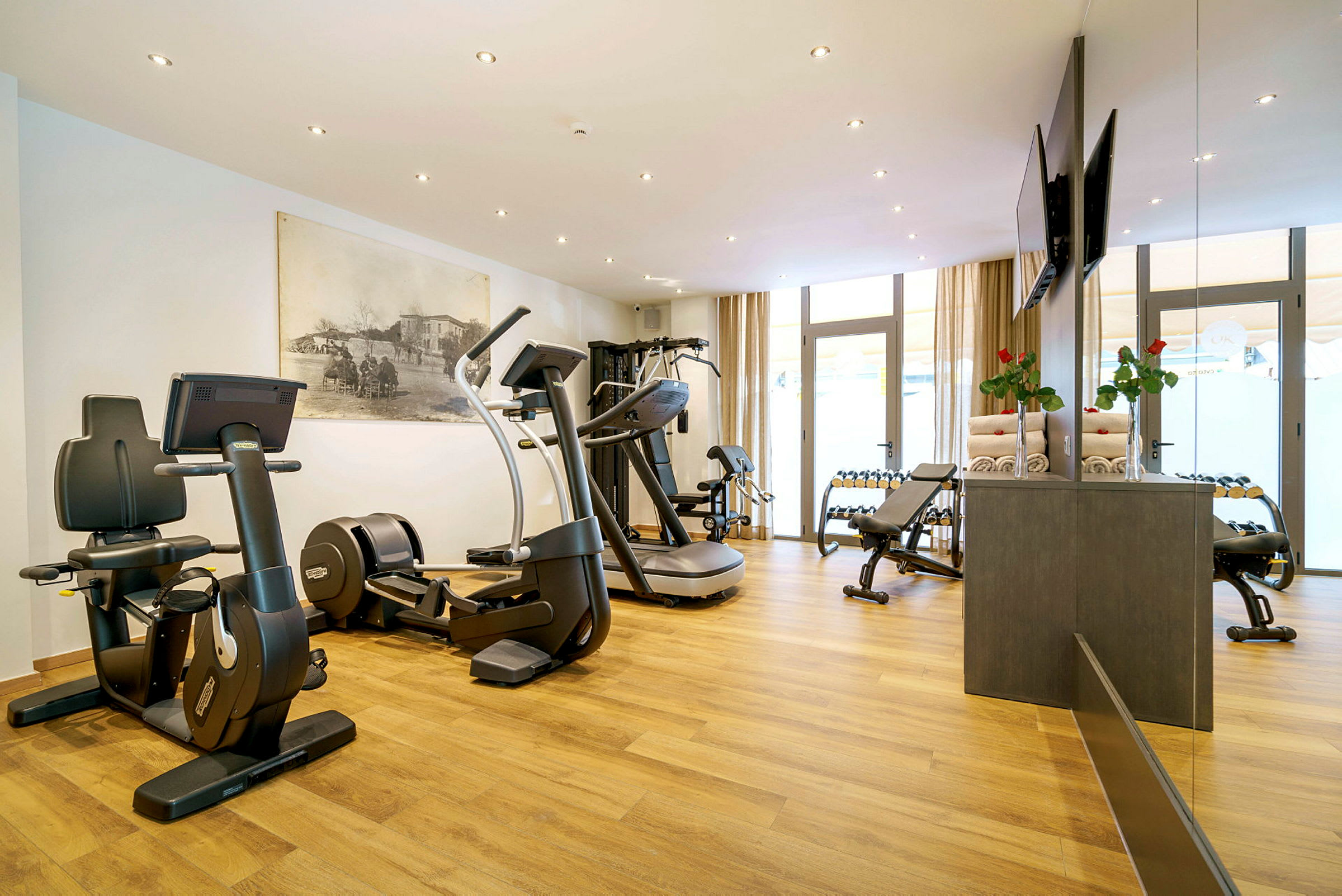 Et moderne fitnesscenter med træningsmaskiner, vægte og trægulv. (AI-genereret tekst)