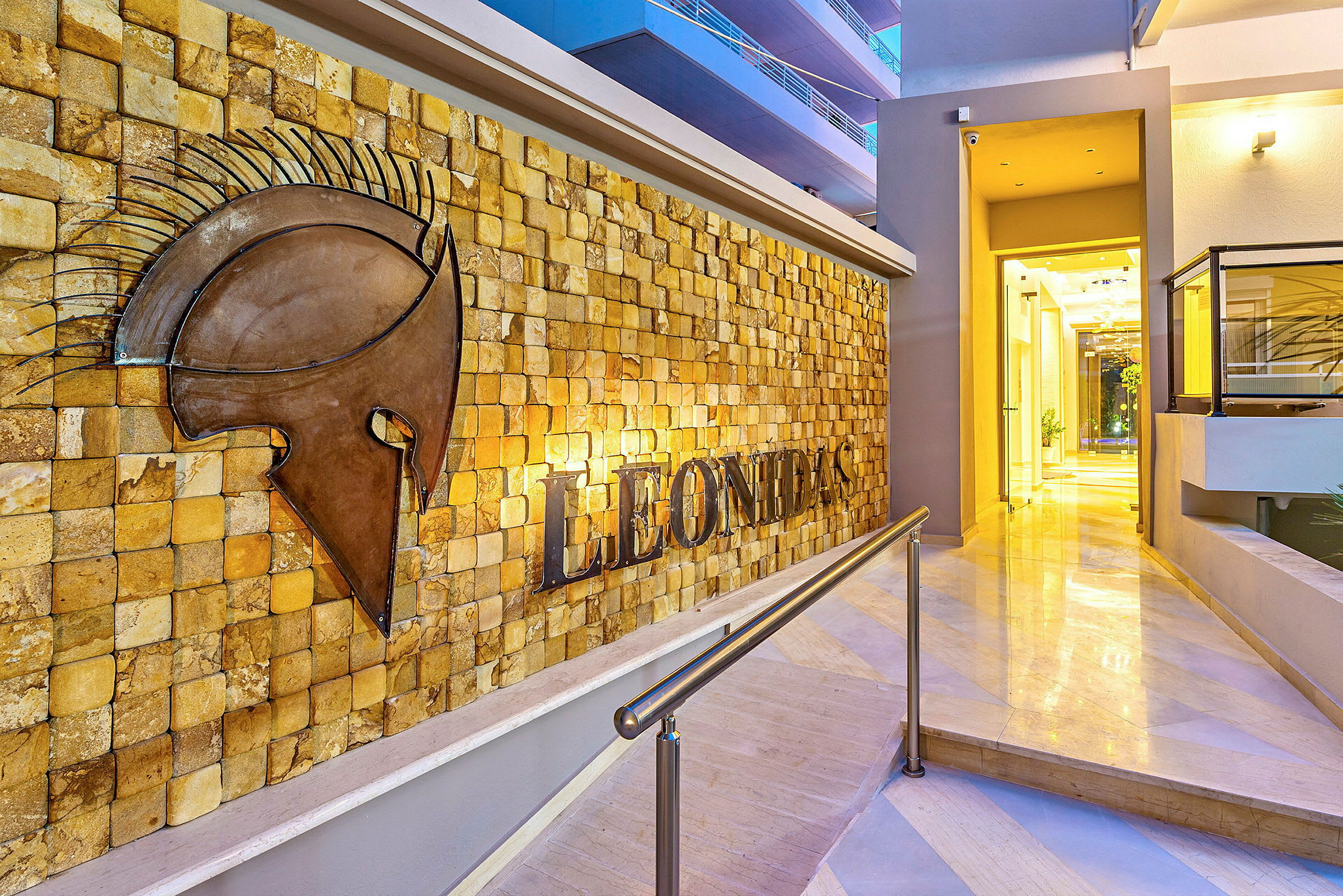 Indgang til Leonidas hotel med en vægdekoration af en hjelm. (AI-genereret tekst)