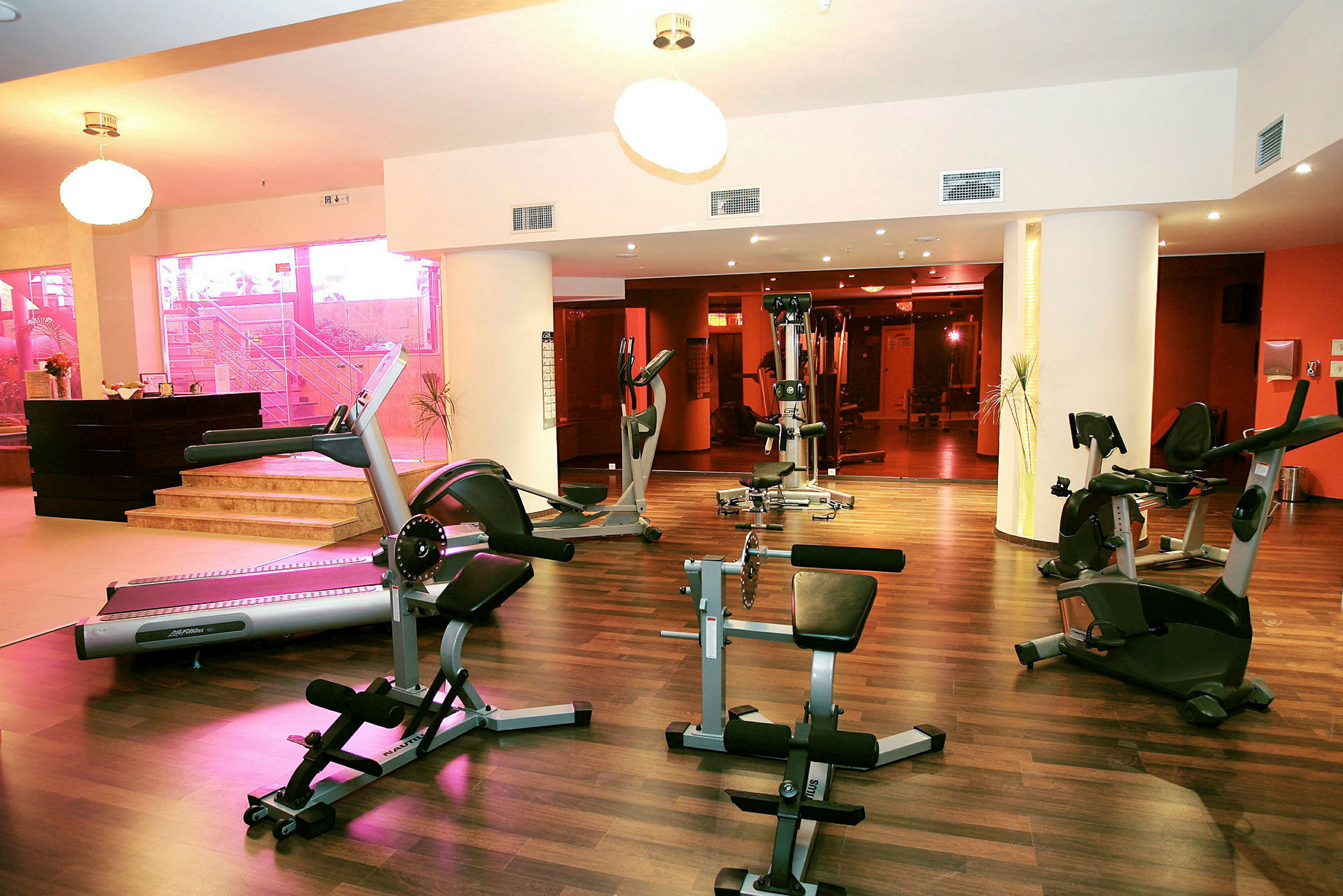 Fitnesscenter med træningsmaskiner og trægulv. (AI-genereret tekst)
