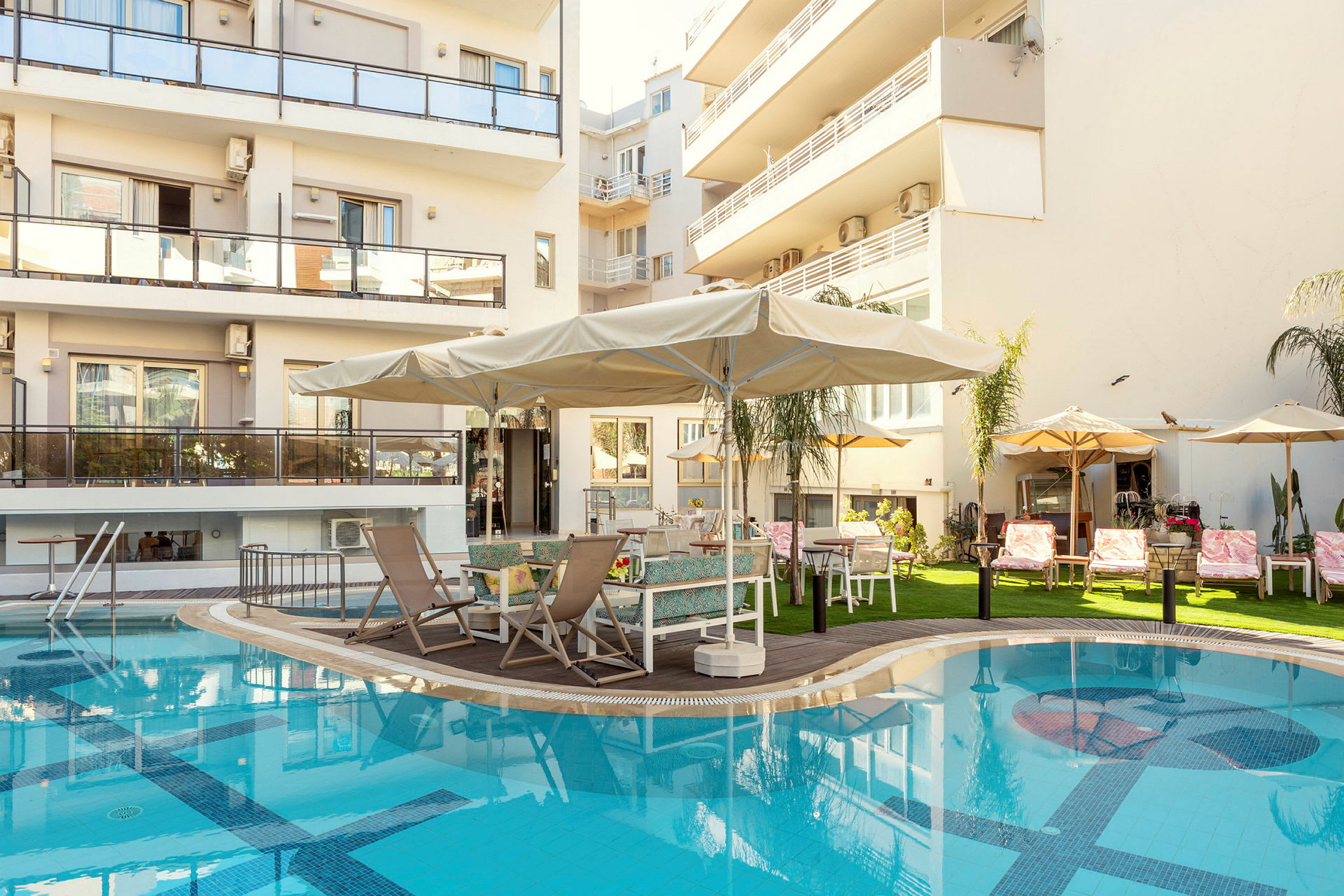 Billede af en bygning med altaner, en pool og en terrasse med liggestole og parasoller. (AI-genereret tekst)