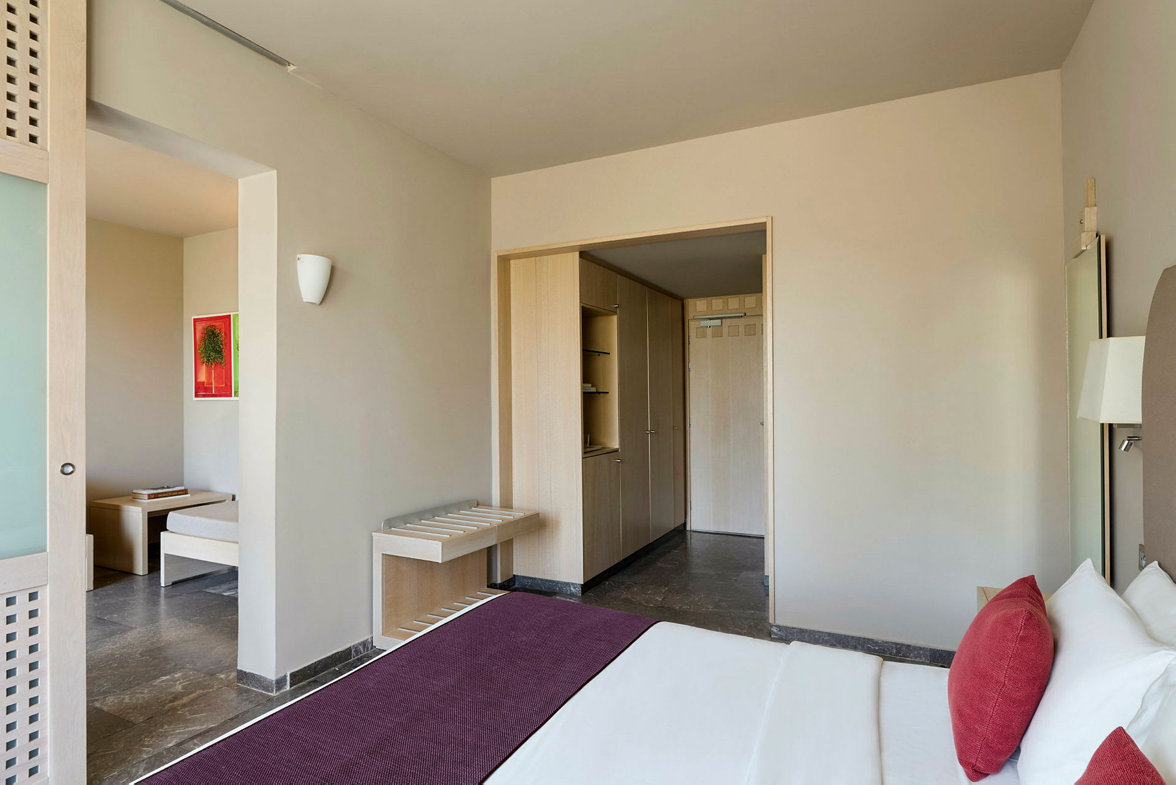 Et hotelværelse med en seng, et skab og en siddeplads. (AI-genereret tekst)