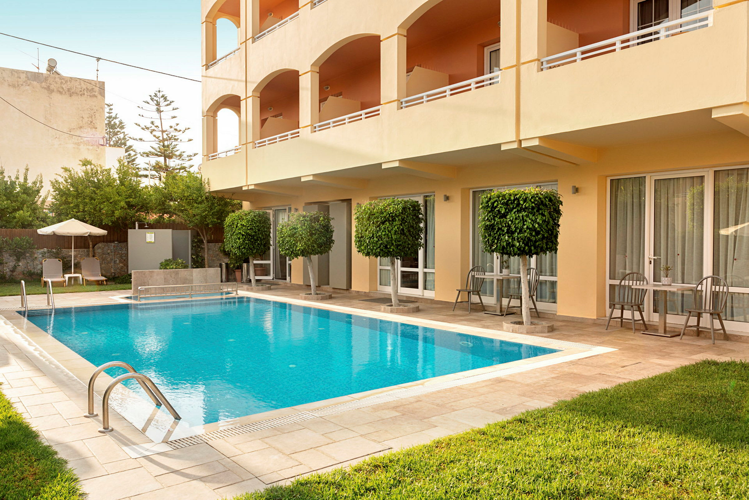 En udendørs pool ved et hotel med liggestole og møblerede terrasser. (AI-genereret tekst)