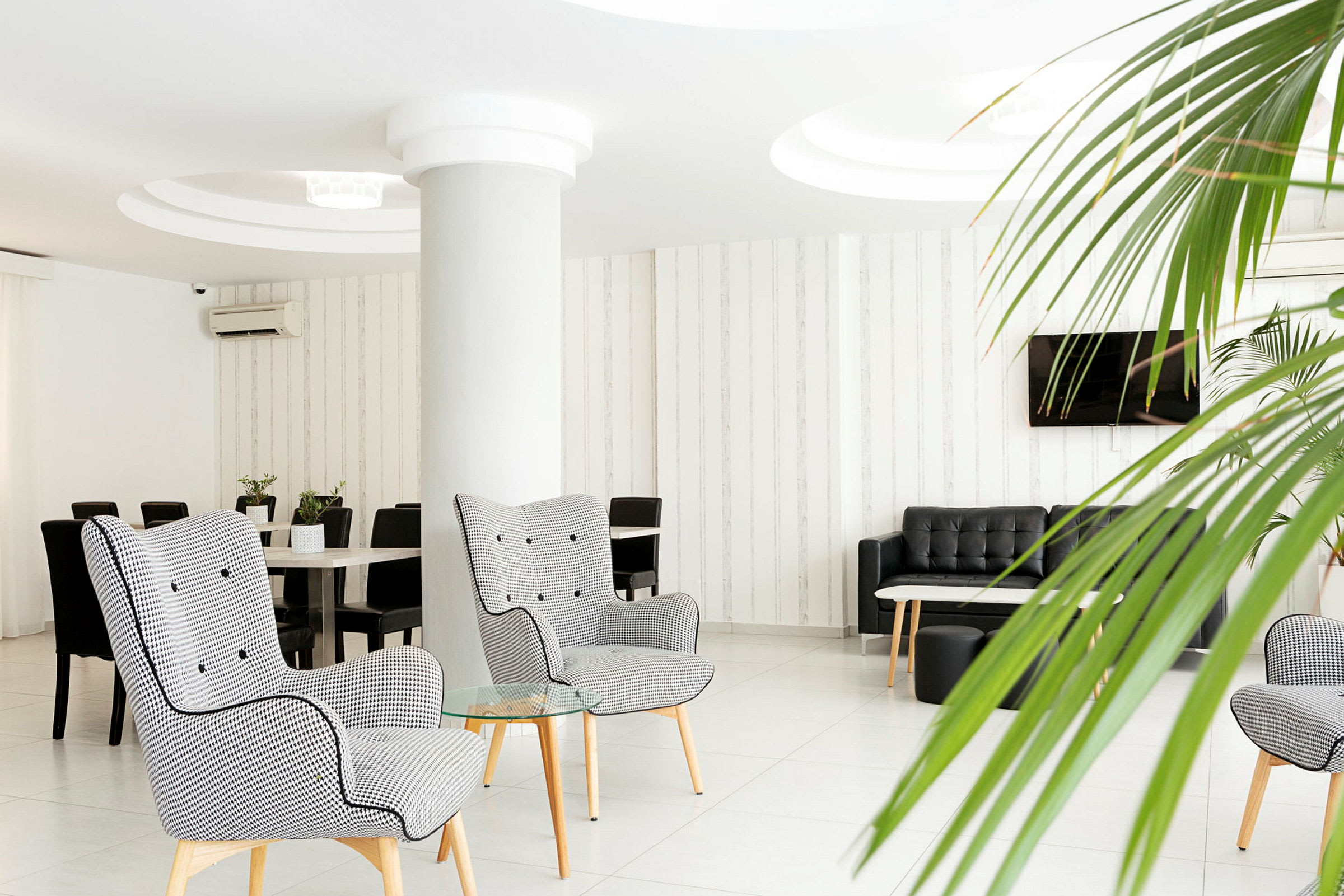 Moderne hotellounge med lænestole, sofaer og planteudsmykning. (AI-genereret tekst)