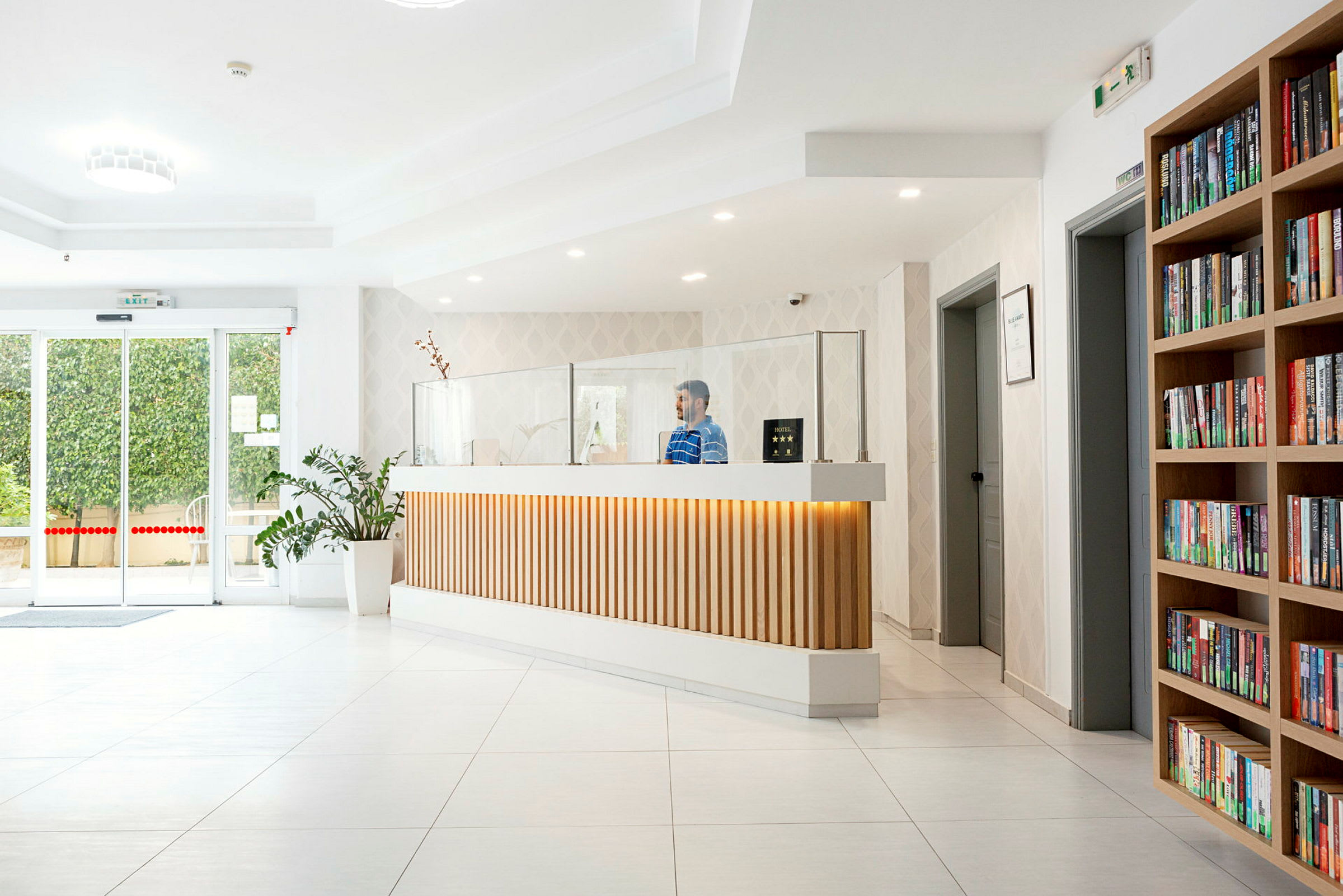 Moderne hotelreception med bogreol og plante. (AI-genereret tekst)