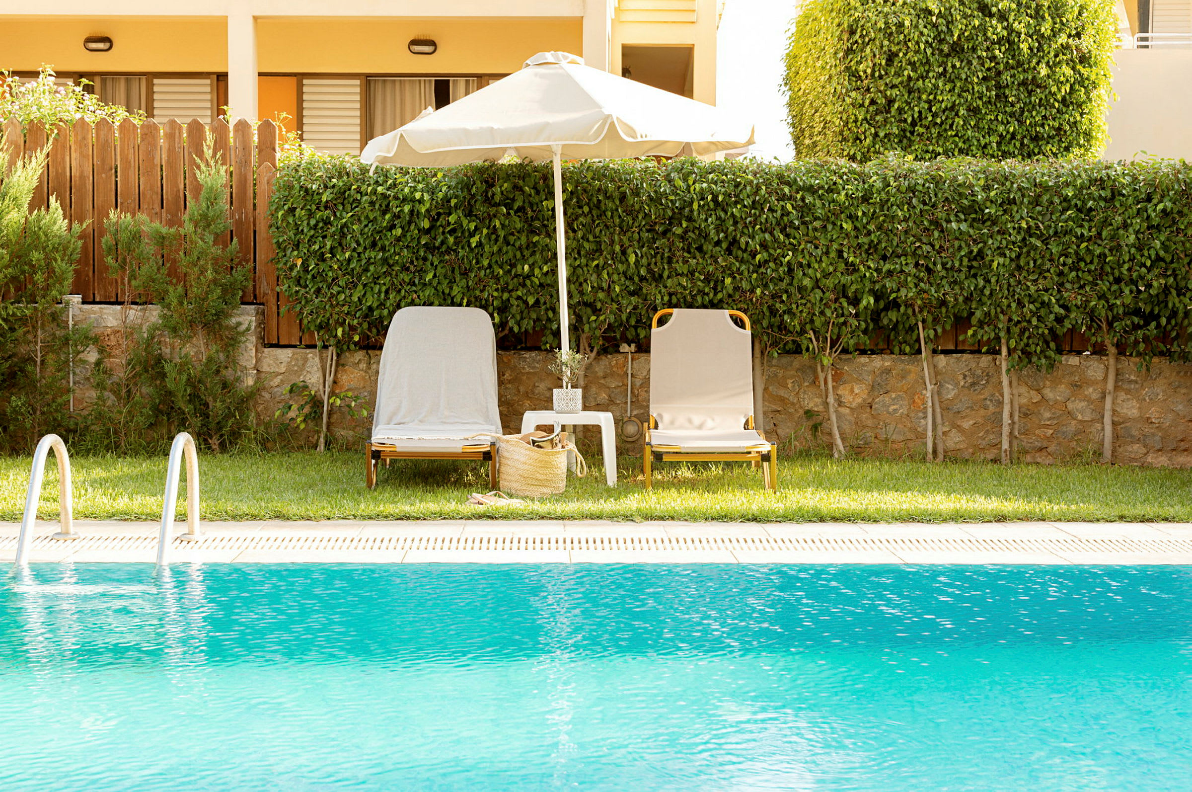 To solsenge ved en pool med en parasol imellem. (AI-genereret tekst)