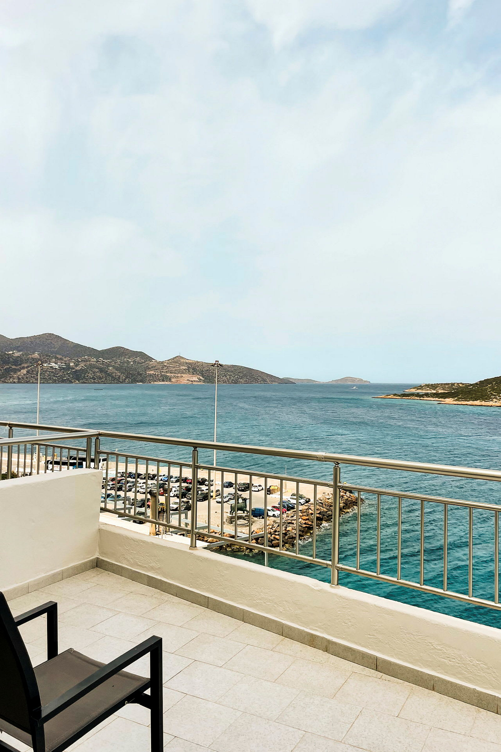 Udsigt fra en balkon mod havet med bjerge i baggrunden. (AI-genereret tekst)