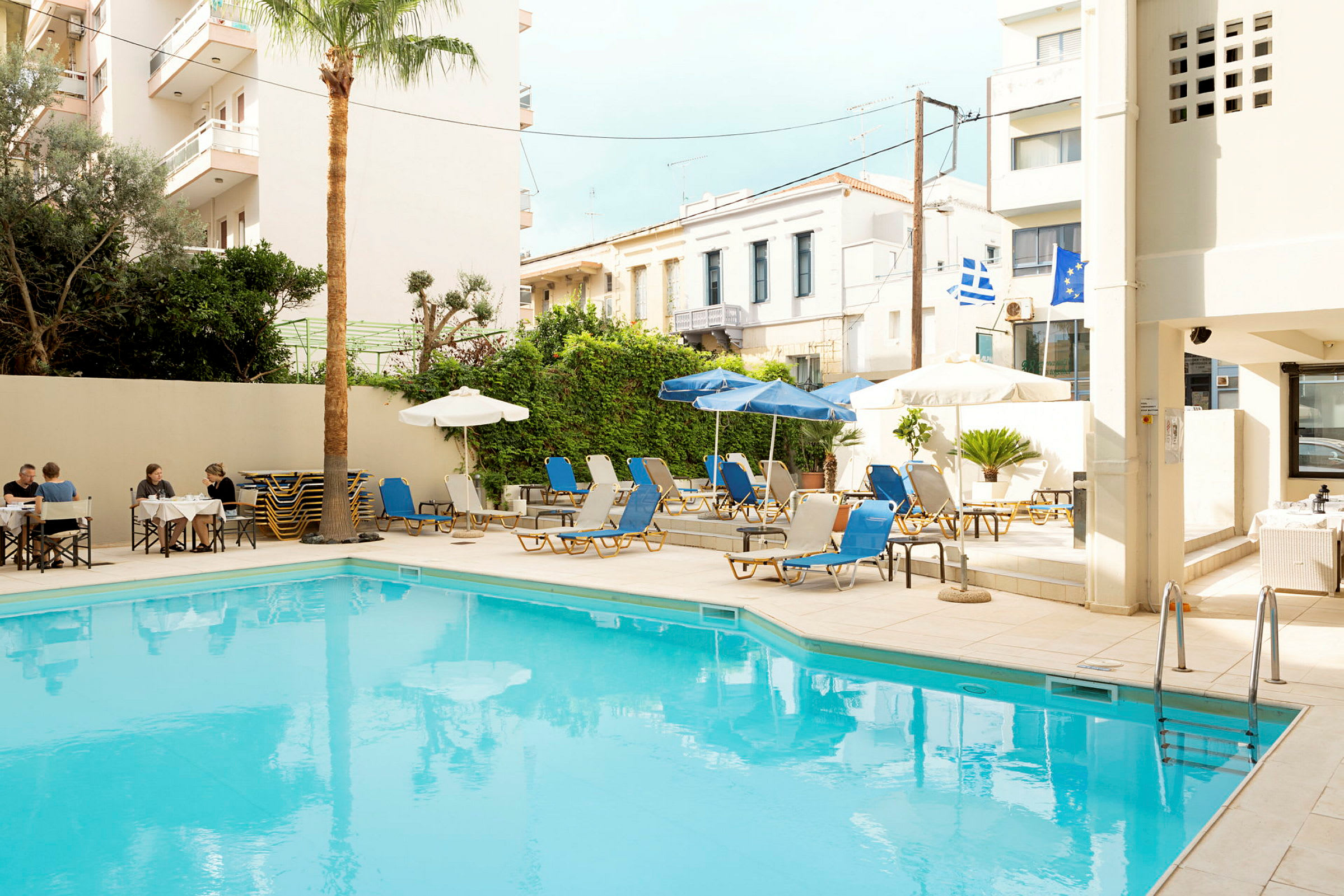 En udendørs swimmingpool omgivet af liggestole og parasoller. (AI-genereret tekst)