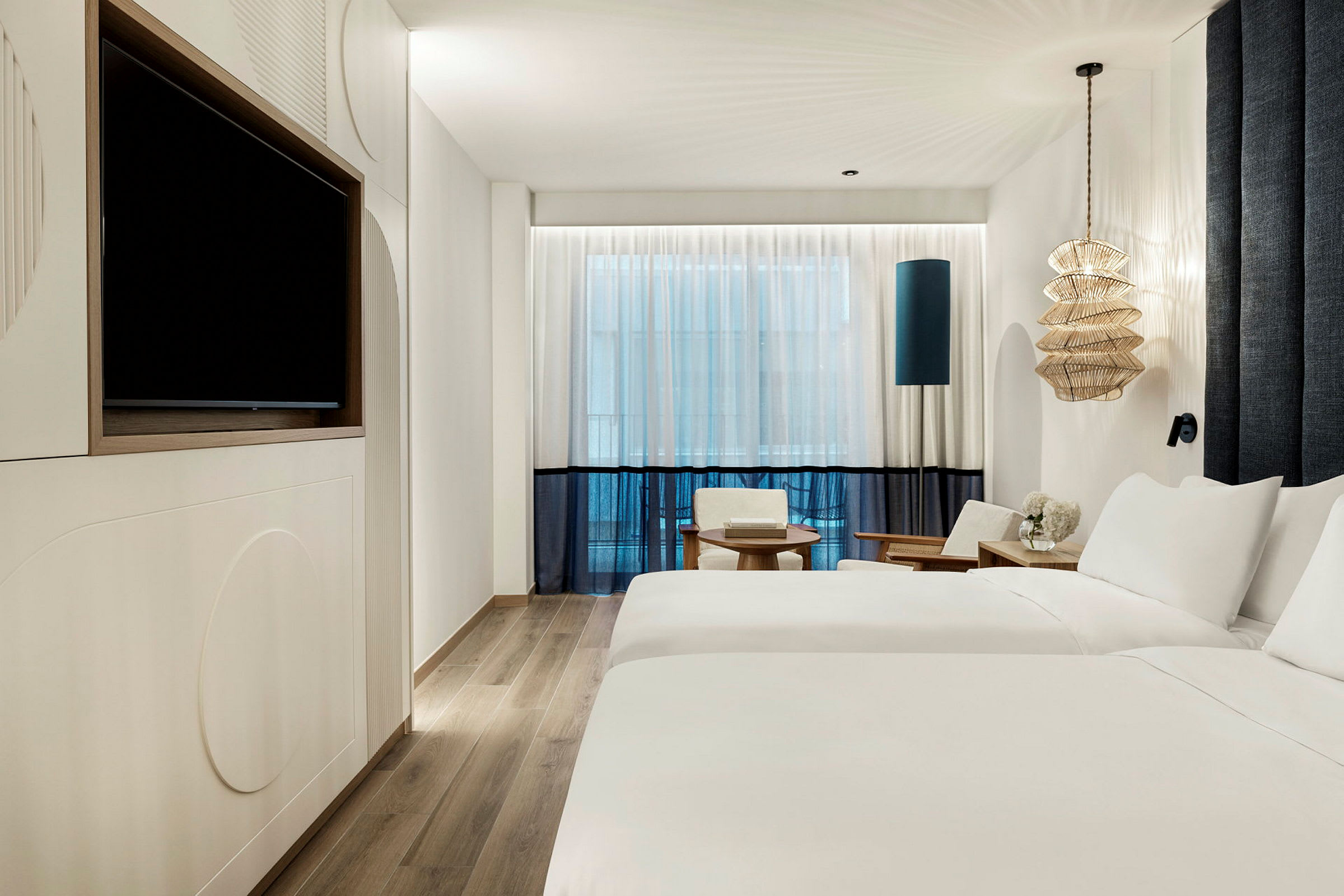 Et moderne hotelværelse med to enkeltsenge, et TV på væggen, siddepladser og en dekorativ lampe. (AI-genereret tekst)