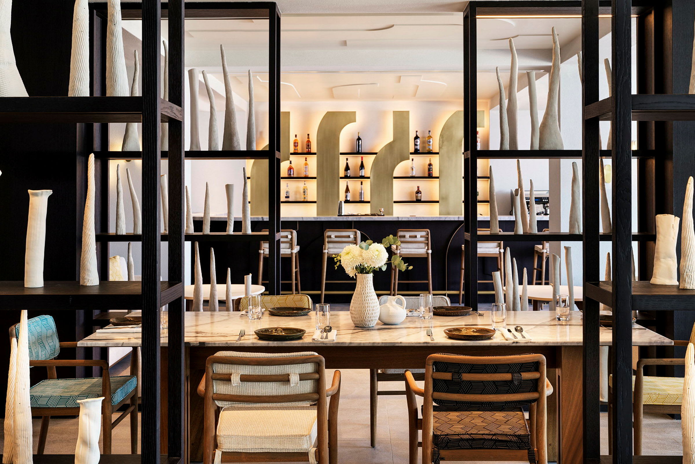 Indretning af en restaurant med dækkede borde, designerstole og kunstgenstande. (AI-genereret tekst)