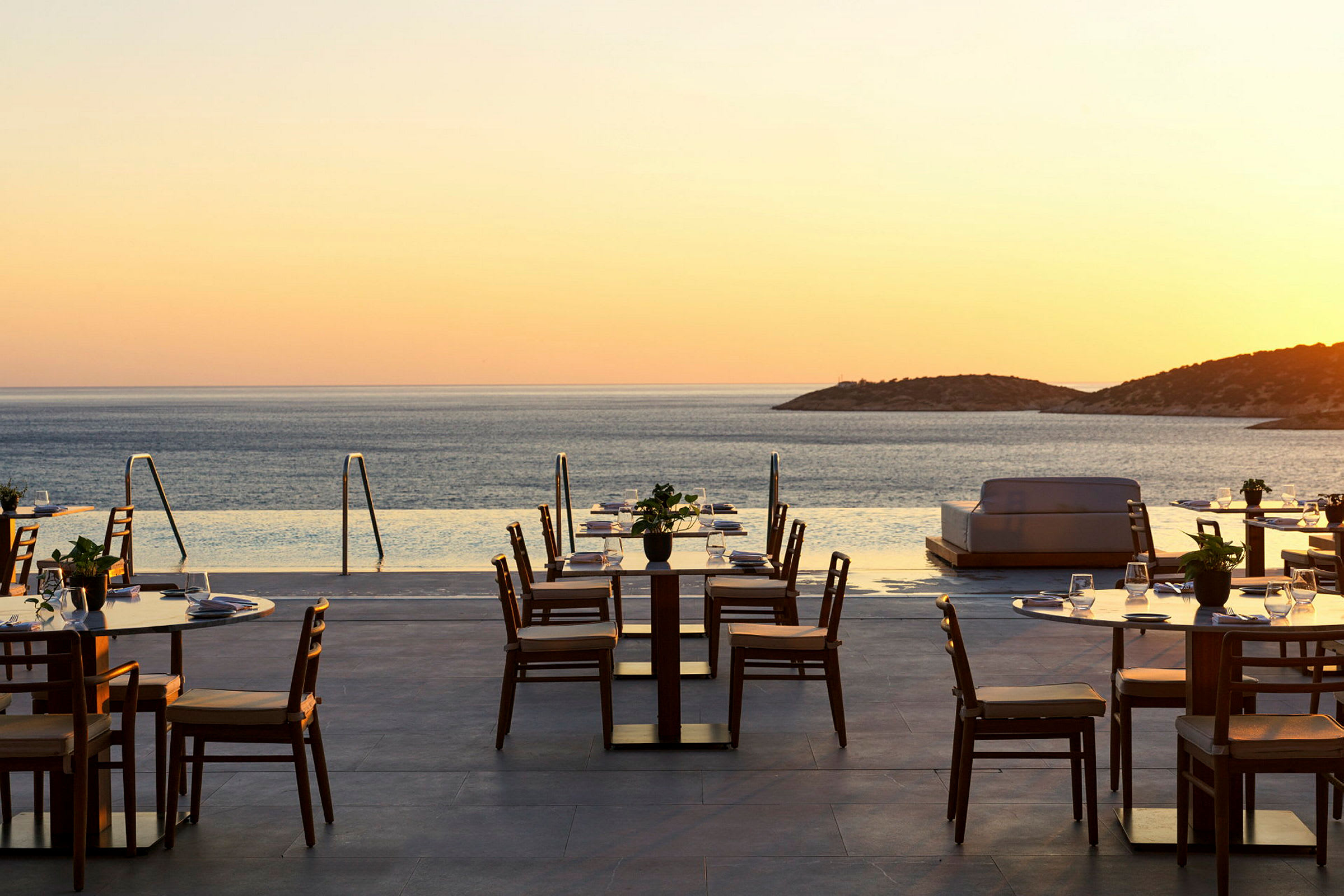 Udendørs restaurant med havudsigt ved solnedgang. (AI-genereret tekst)
