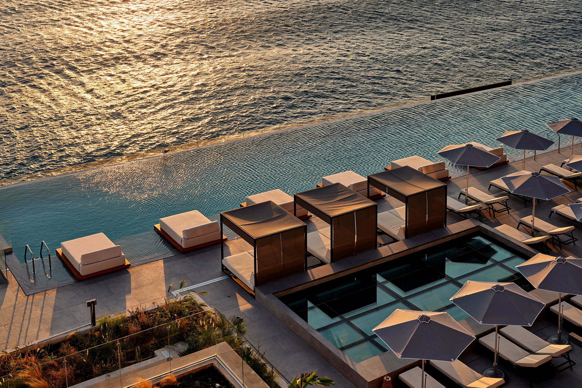 Udsigt over solsenge og skyg-givende parasoller ved en infinitypool med havet i baggrunden. (AI-genereret tekst)