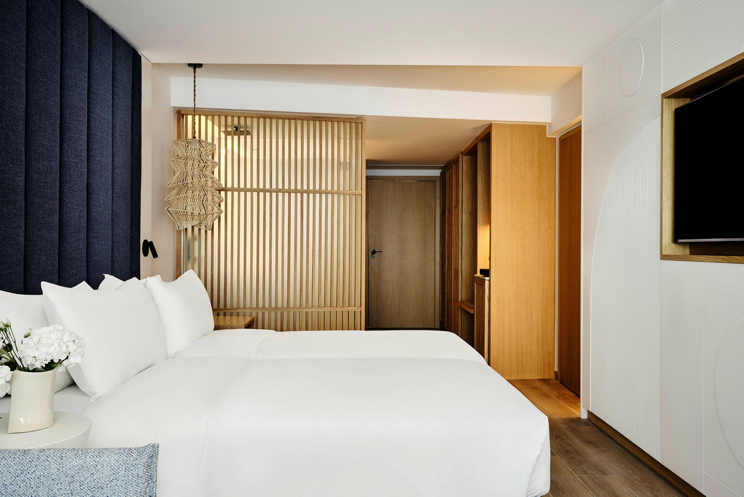 Billede af et moderne hotelværelse med en seng med hvidt sengetøj og trædetaljer. (AI-genereret tekst)