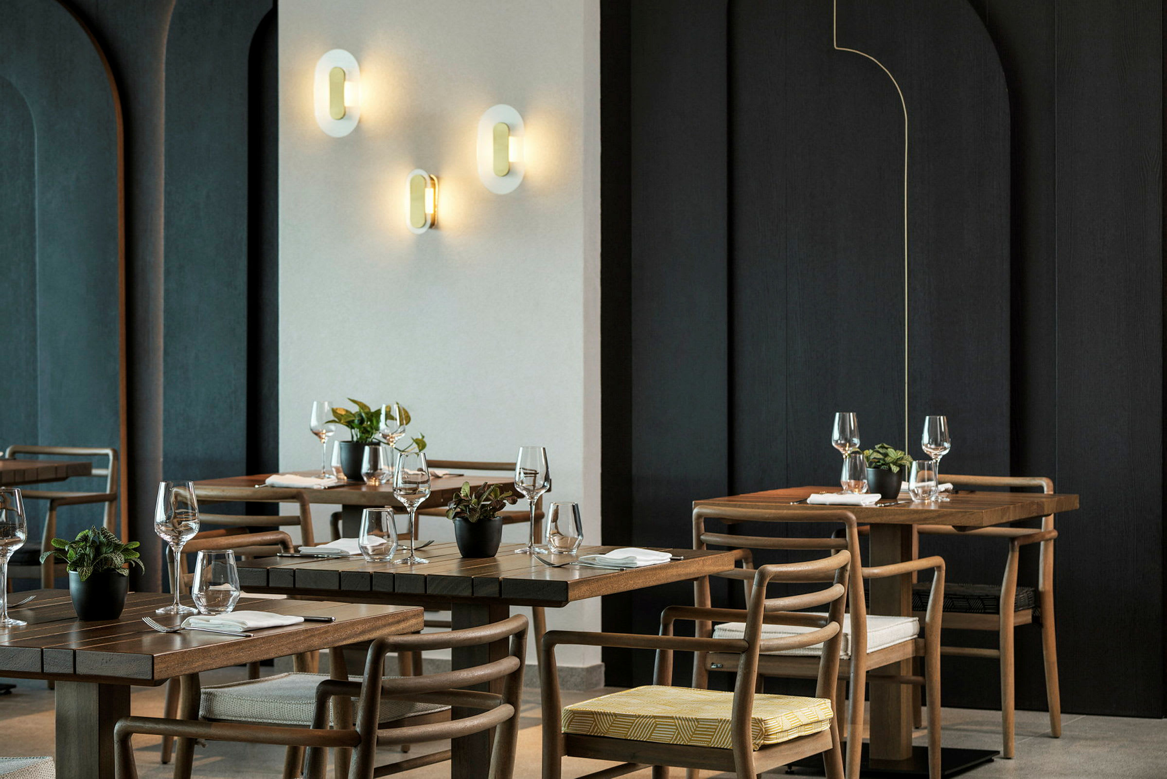 En elegant restaurant med træborde, stole og vægbelysning. (AI-genereret tekst)