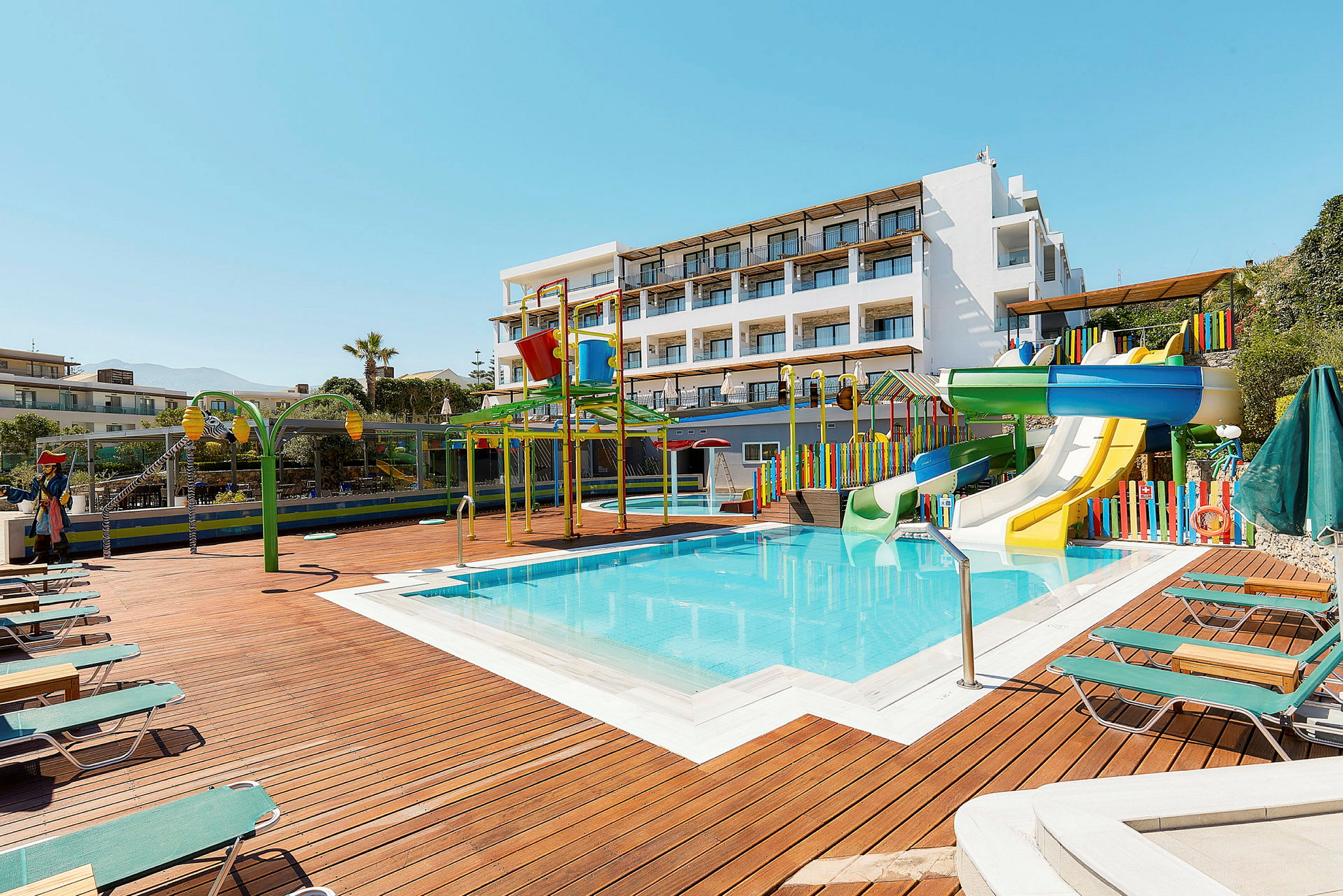 En udendørs pool med vandrutsjebaner og farverige legeudstyr ved et hotel. (AI-genereret tekst)