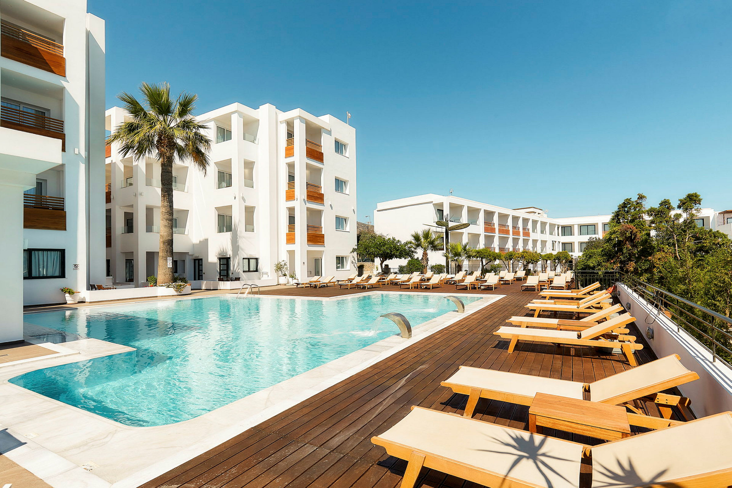 Hotelområde med swimmingpool og liggestole. (AI-genereret tekst)