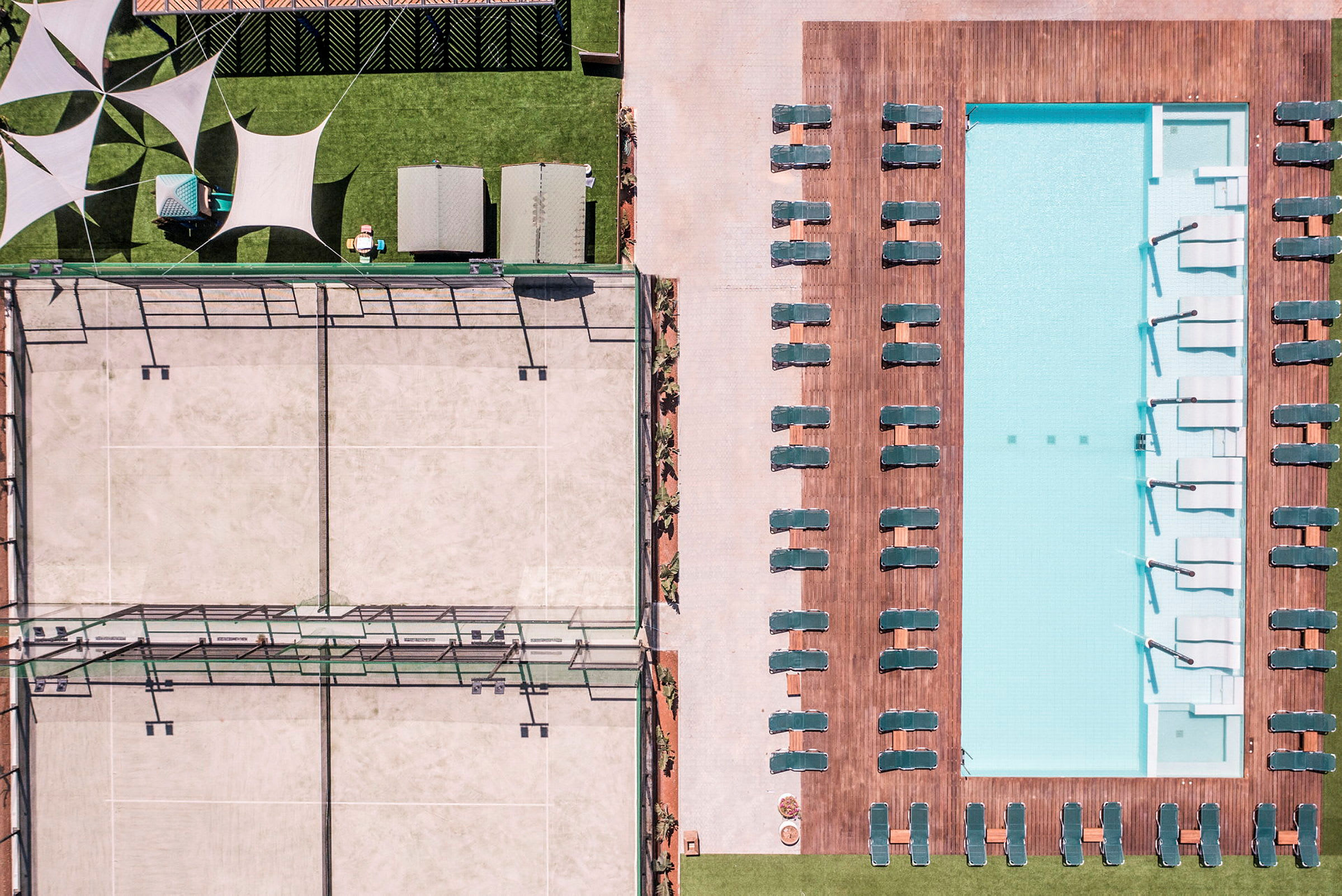 Luftfoto af en pool med liggestole og en tennisbane ved siden af. (AI-genereret tekst)
