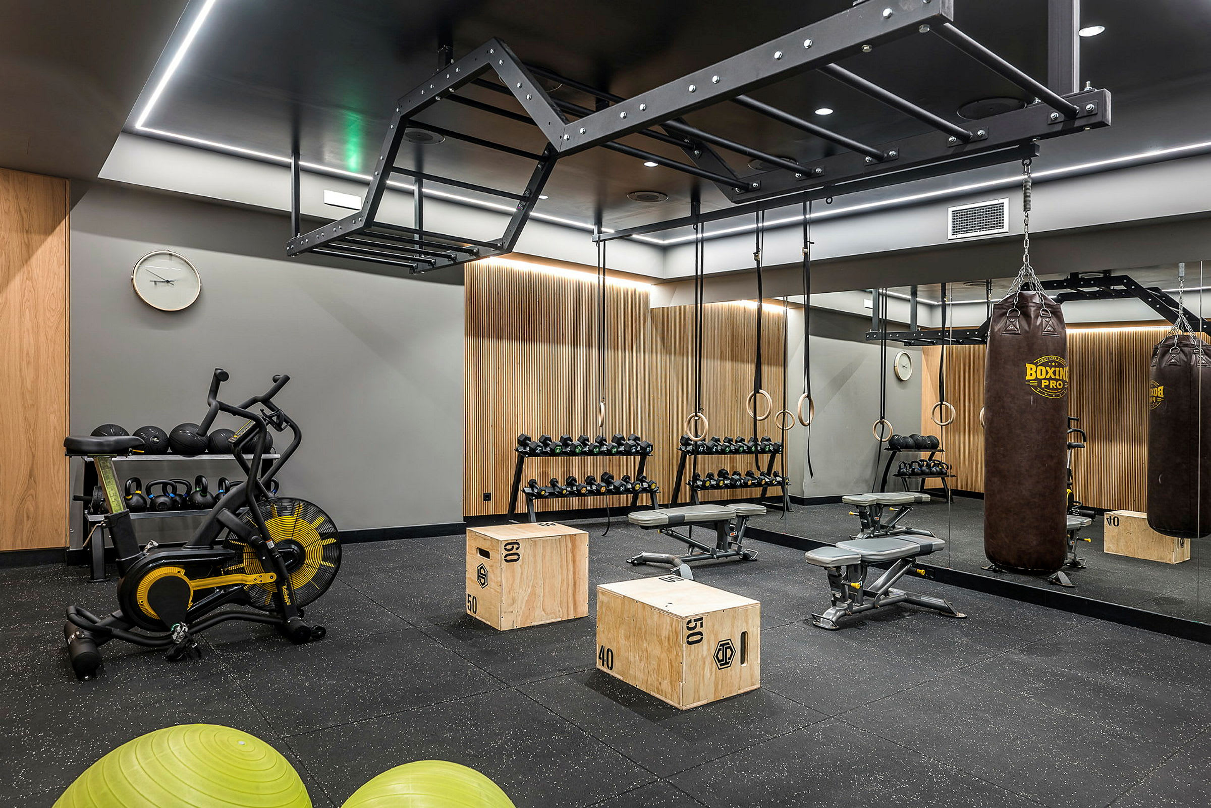 Et fitnesscenter med træningsudstyr, herunder en boksepude, håndvægte og pilatesbolde. (AI-genereret tekst)