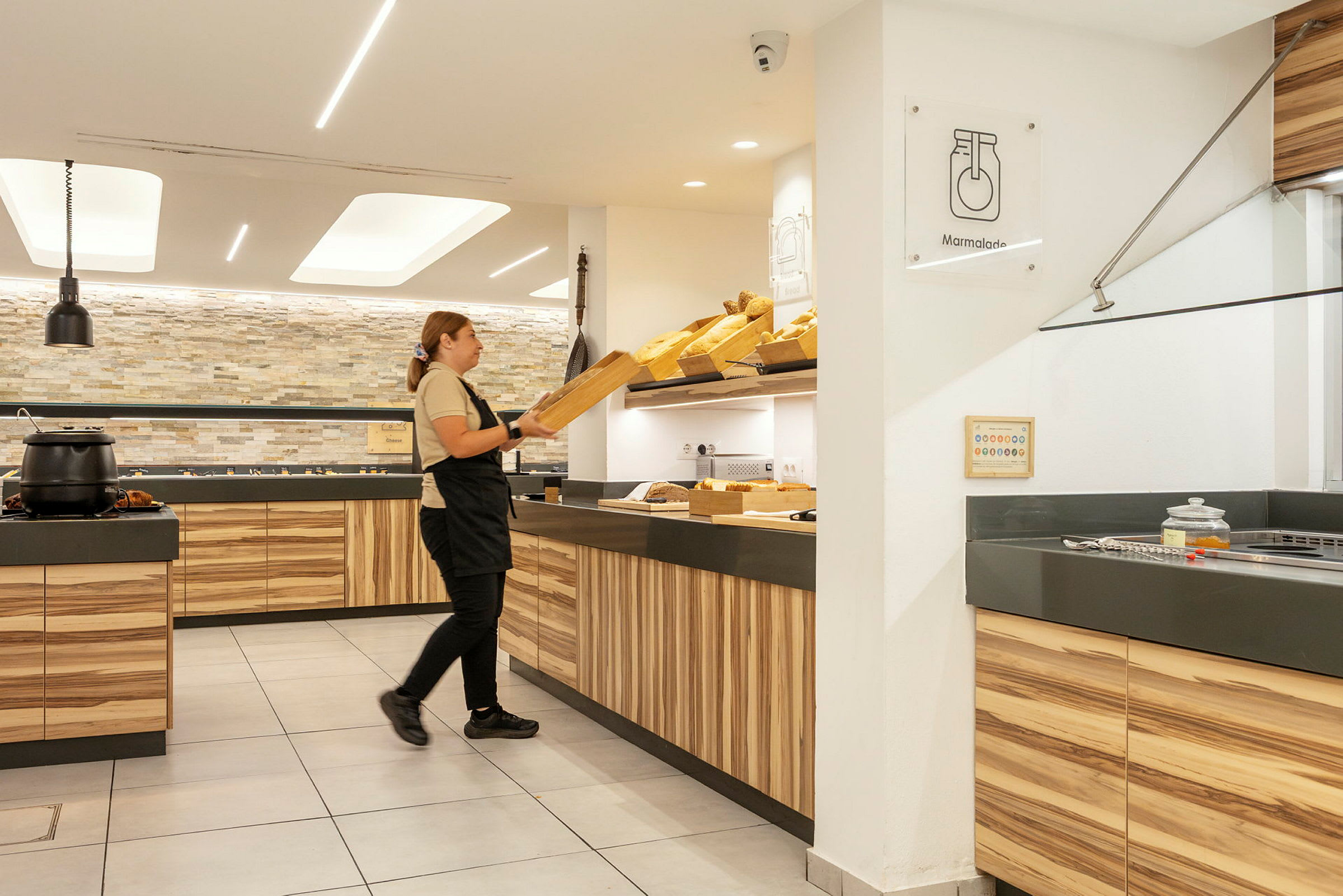 En person organiserer brød i et lyst og moderne serveringsområde. (AI-genereret tekst)