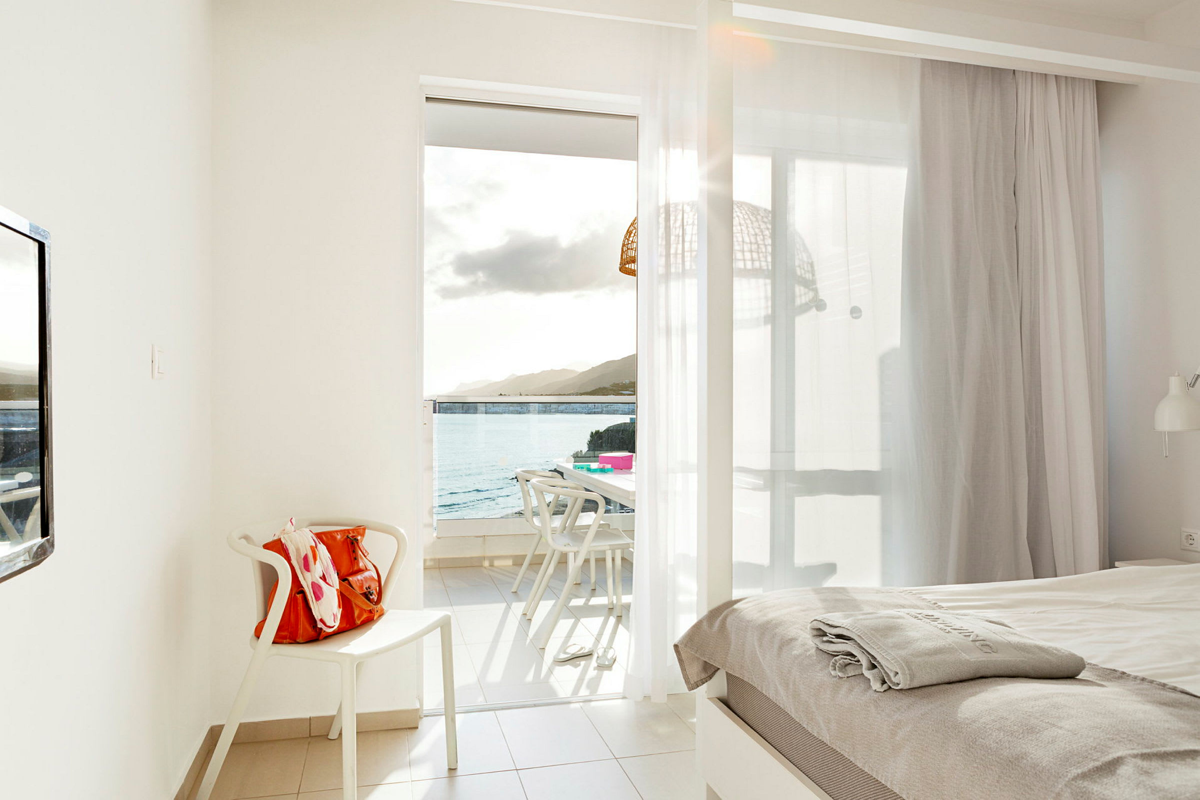 Hotelværelse med udsigt til havet gennem en åben altandør. (AI-genereret tekst)
