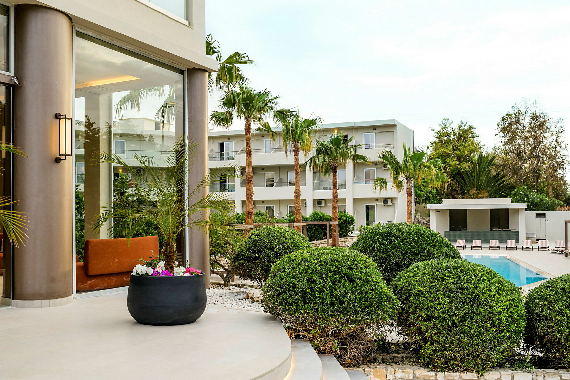 Hotelområde med palmer, pool og grønne områder. (AI-genereret tekst)