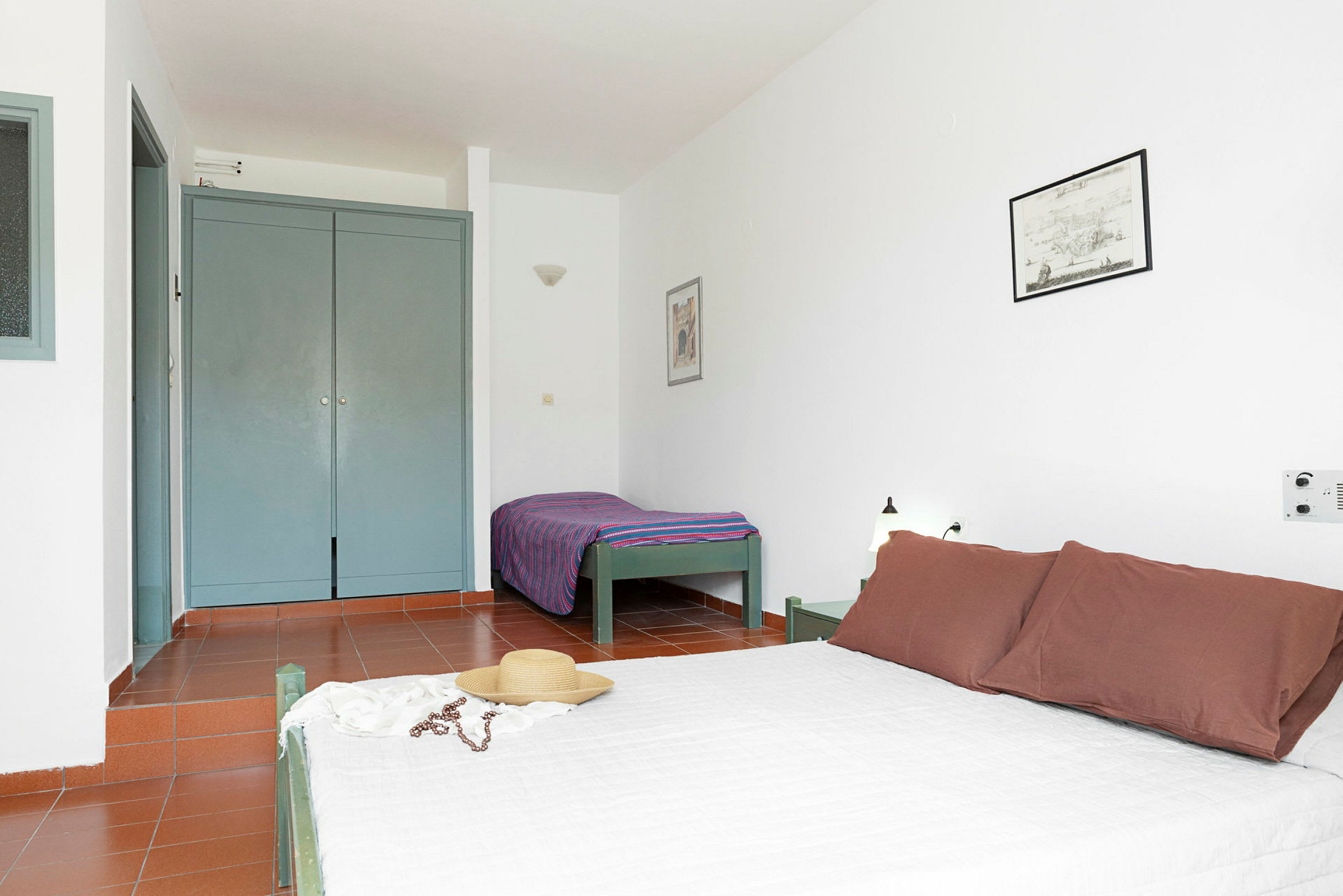 Et hotelværelse med en dobbeltseng og enkeltseng, garderobe og minimalistisk indretning. (AI-genereret tekst)