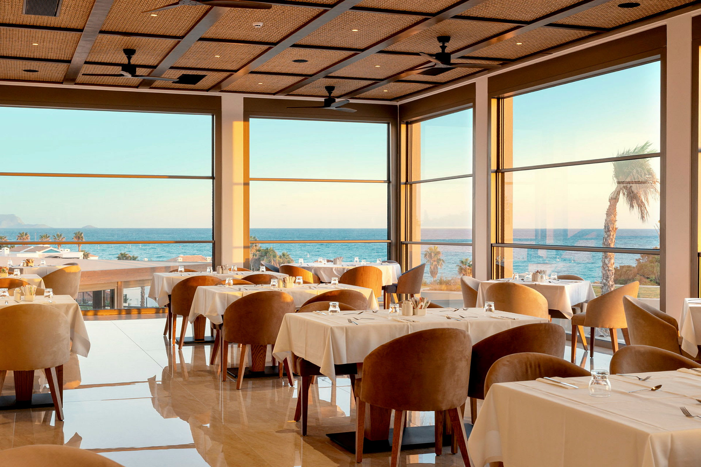 En elegant indendørs restaurant med store vinduer og havudsigt. (AI-genereret tekst)