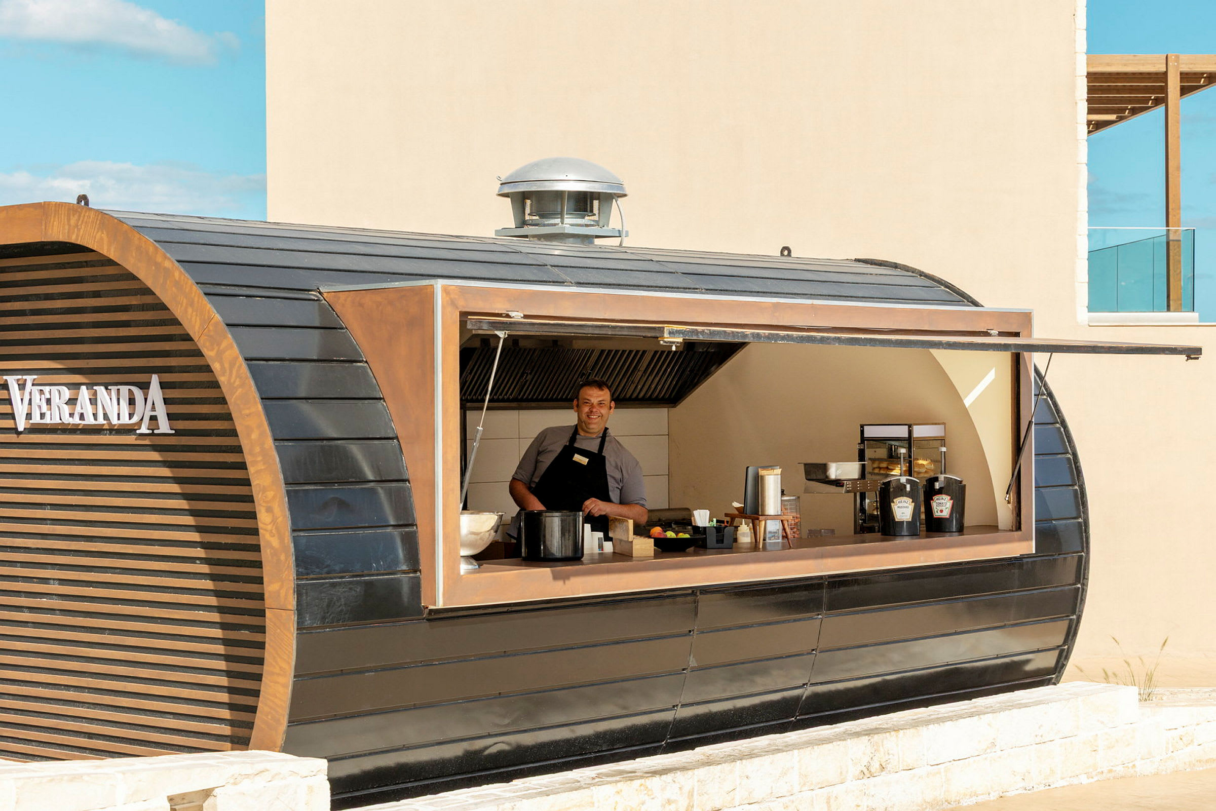 En person arbejder i en serveringskiosk med moderne design kaldet Veranda. (AI-genereret tekst)