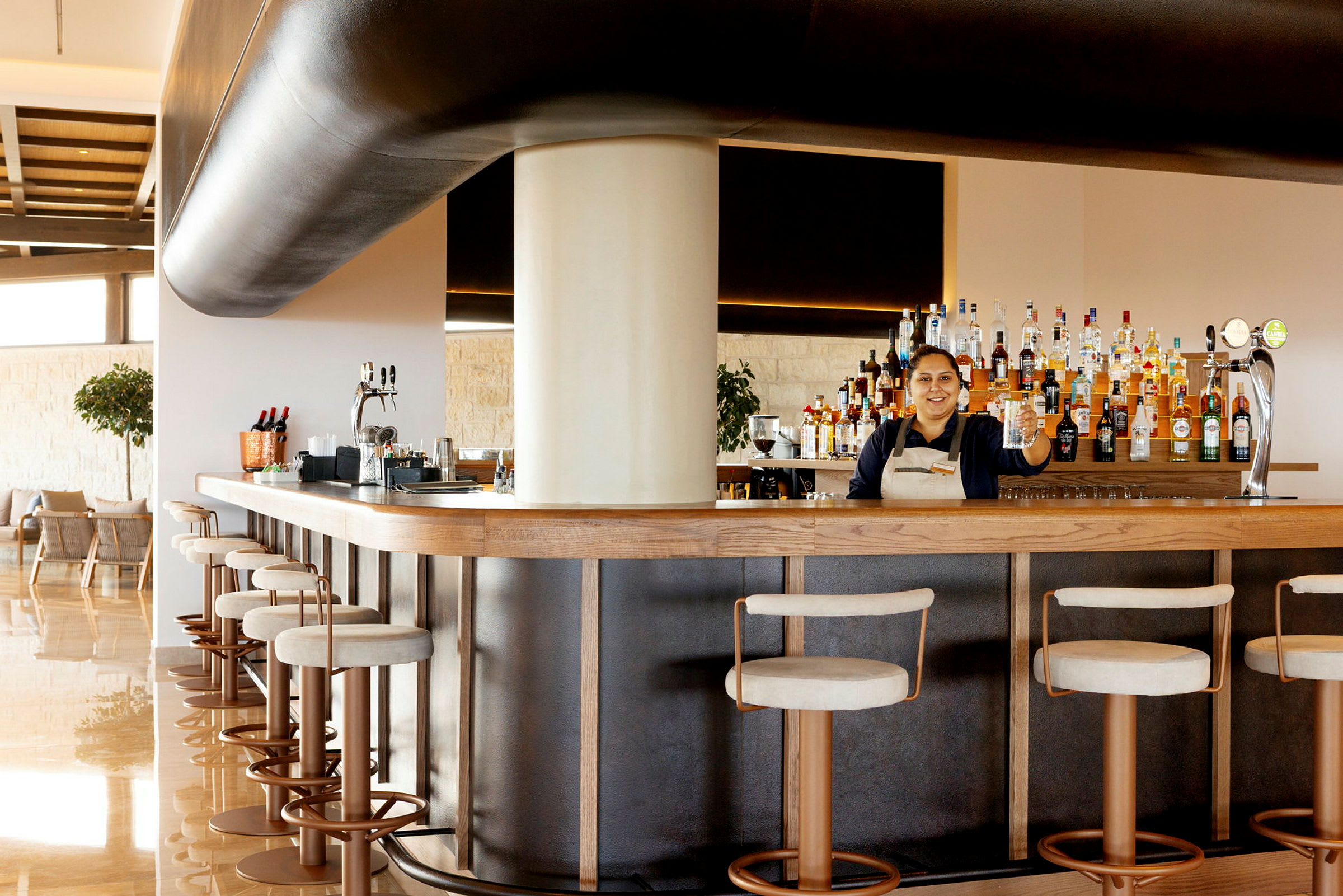 En bartender står bag en veludstyret bar med barstole foran. (AI-genereret tekst)