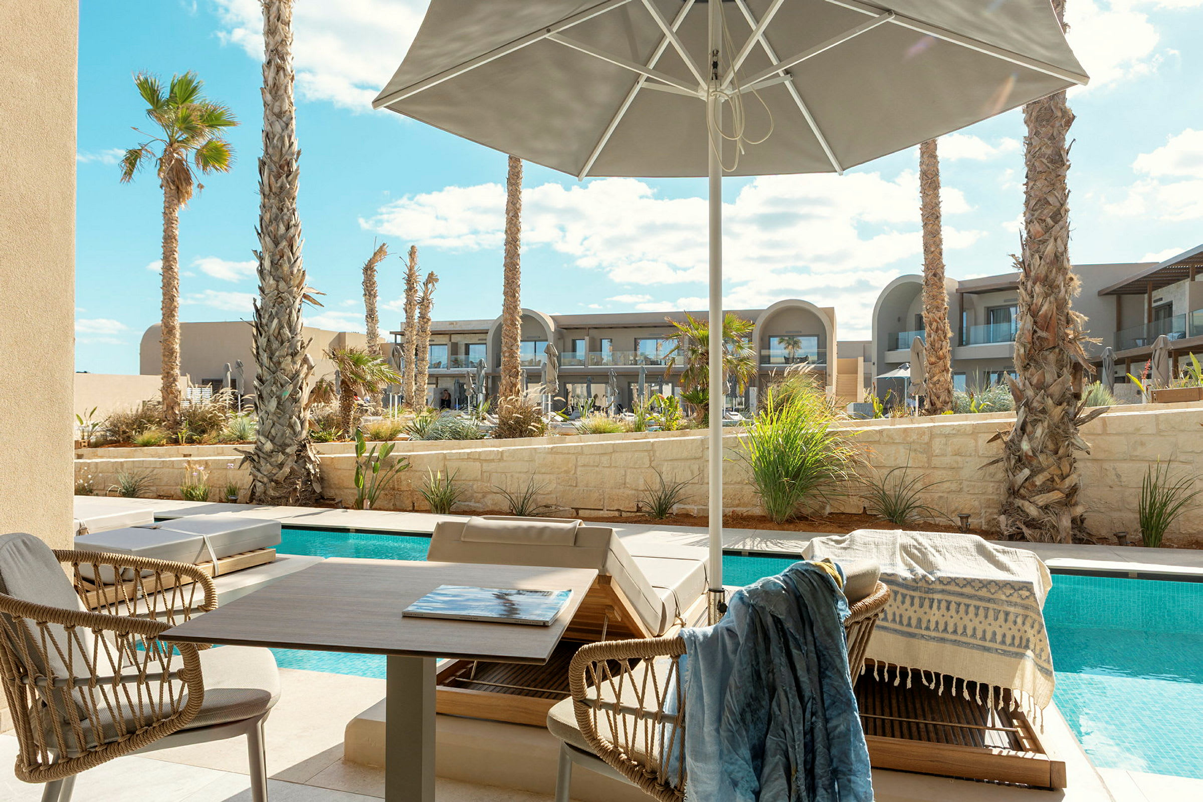 Solterrasse med udsigt over pool og palmer, med udendørsmøbler under parasol. (AI-genereret tekst)