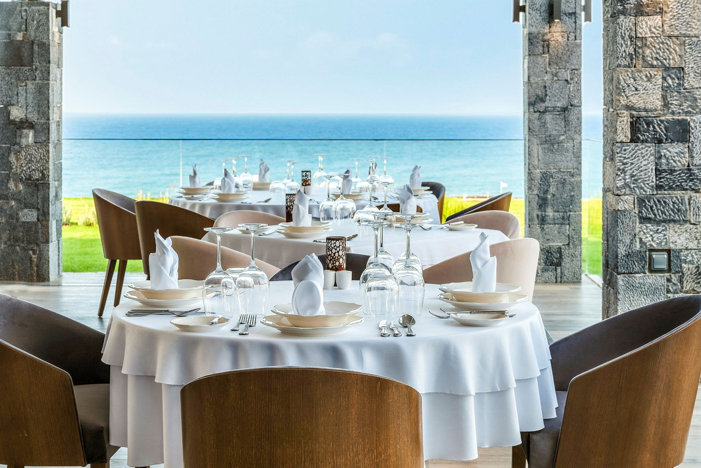 Billede af en restaurant med dækkede borde, udsigt over havet. (AI-genereret tekst)