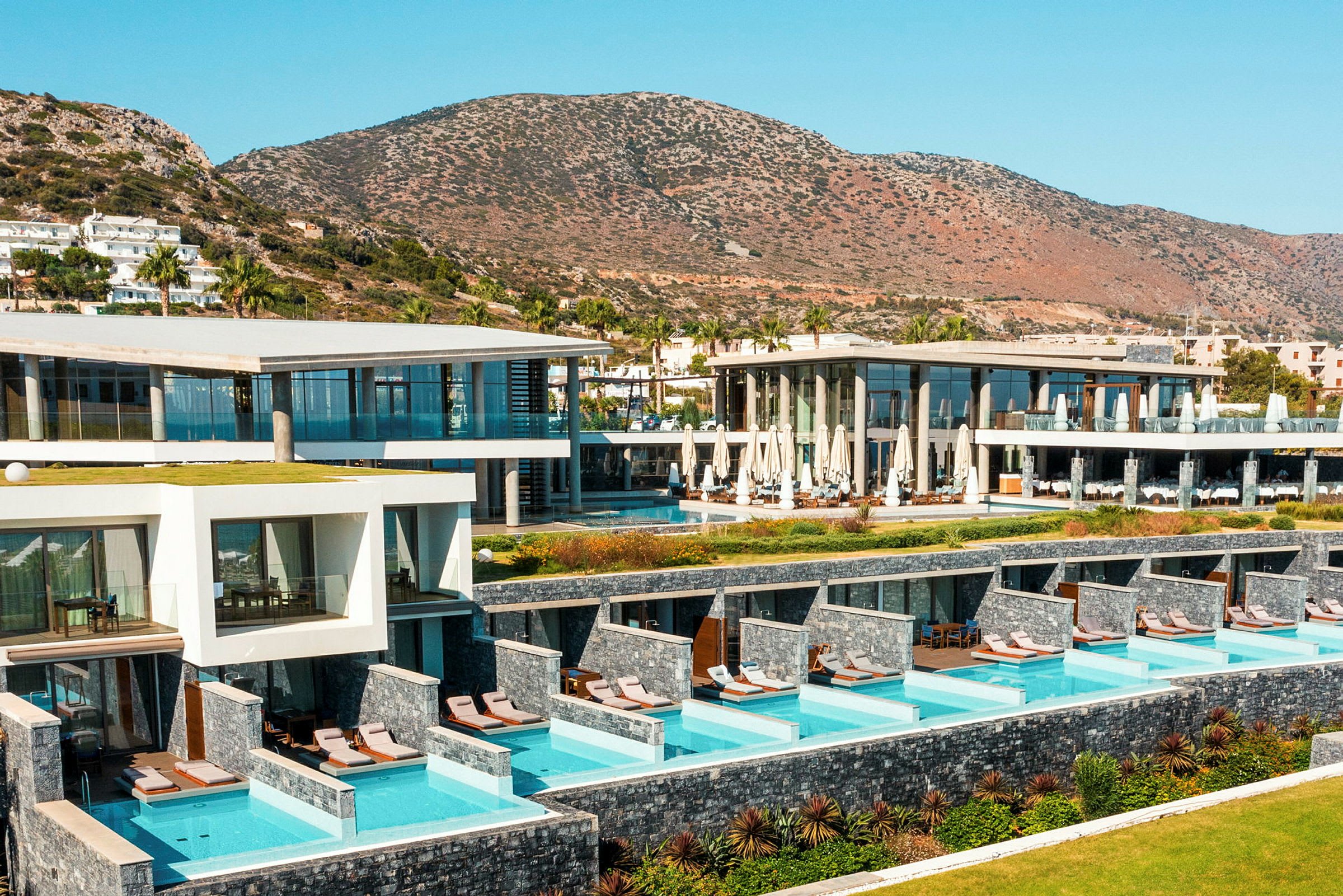 Hotelbygninger med private pools og bjerge i baggrunden. (AI-genereret tekst)