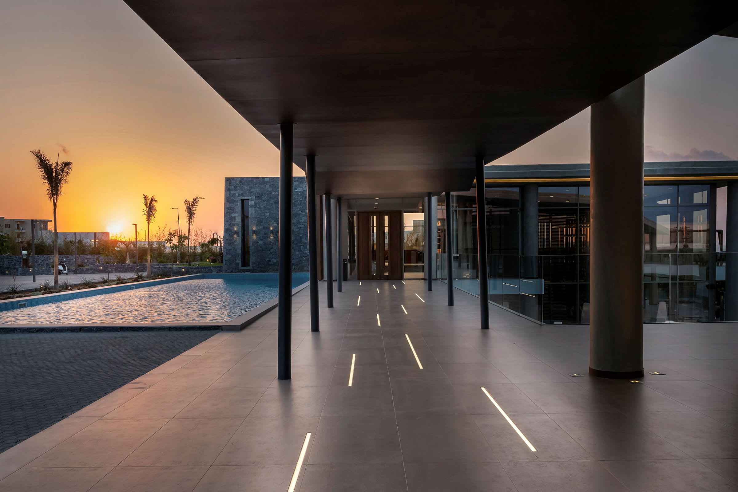 Moderne hotelområde ved solnedgang med pool og gangsti. (AI-genereret tekst)