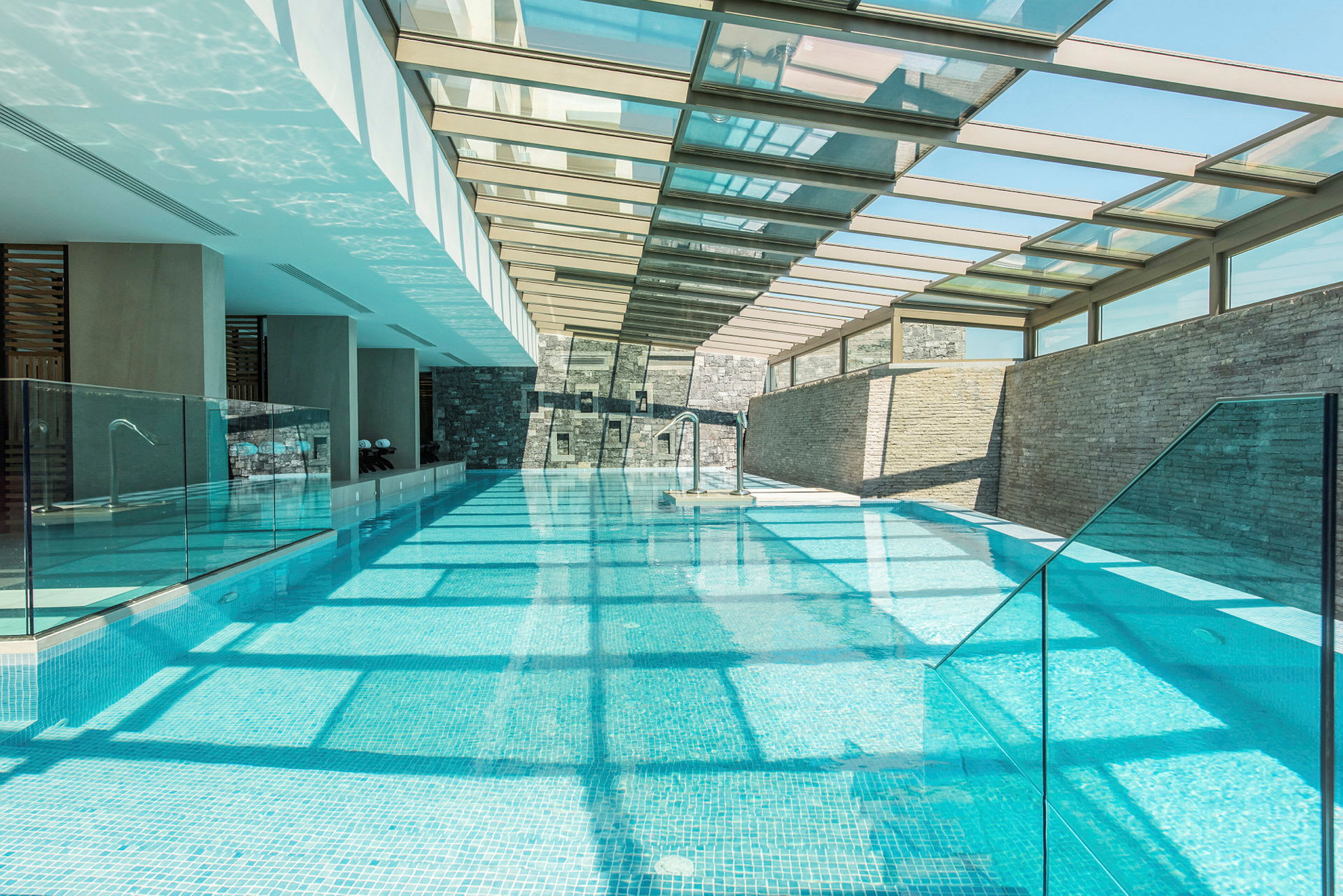 En lang indendørs pool med glastag, der lukker lys ind. (AI-genereret tekst)