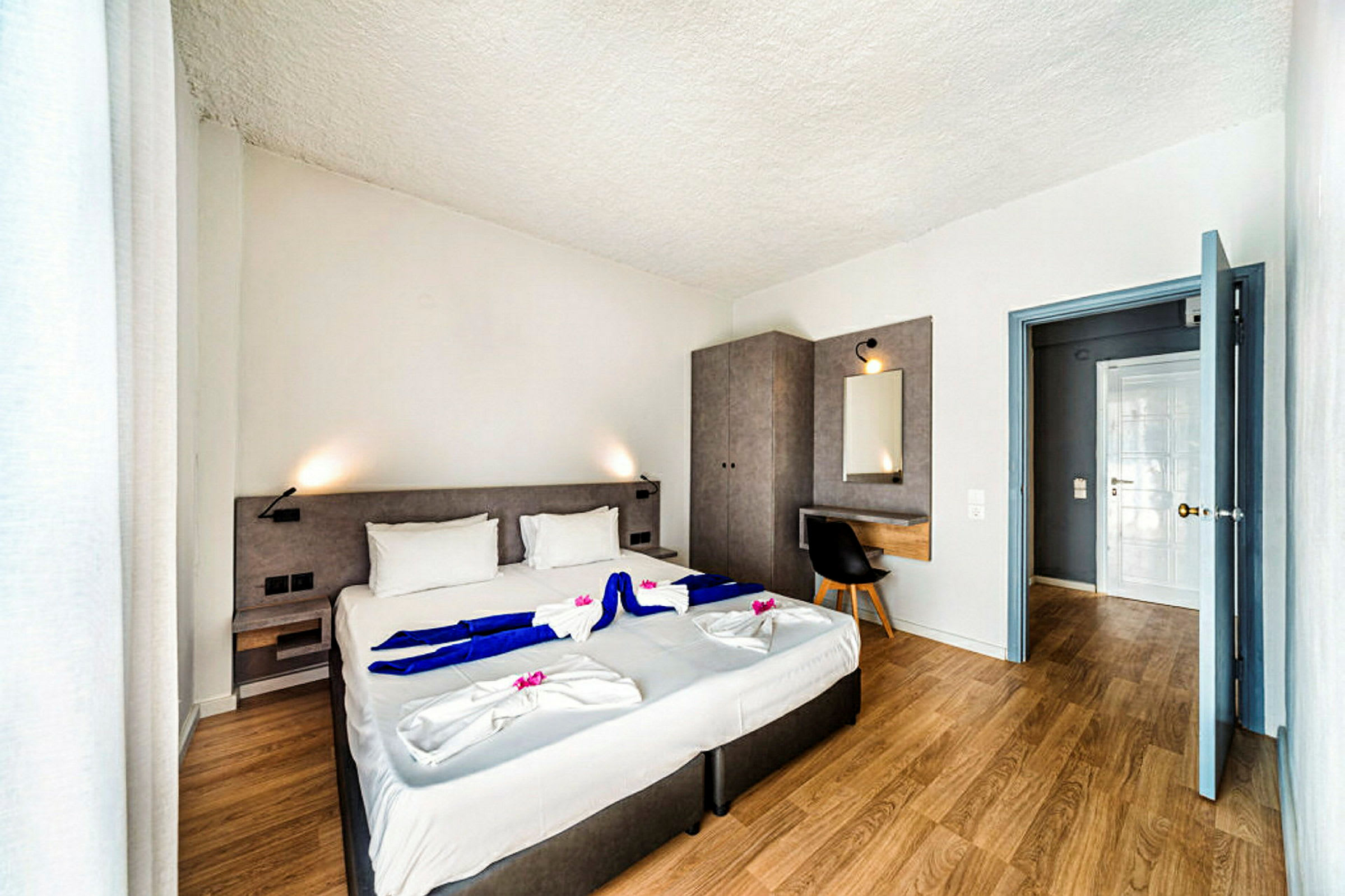 Moderne hotelværelse med dobbeltseng, skrivebord og garderobe. (AI-genereret tekst)